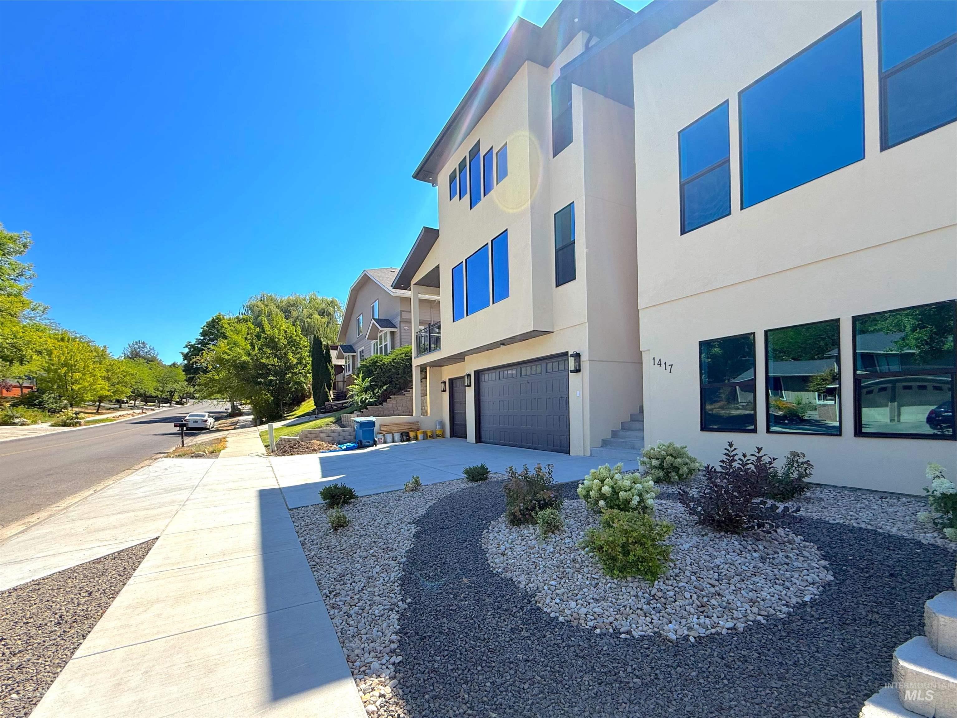 View of front of property featuring a garage, stucco siding, concrete driveway, and a residential view