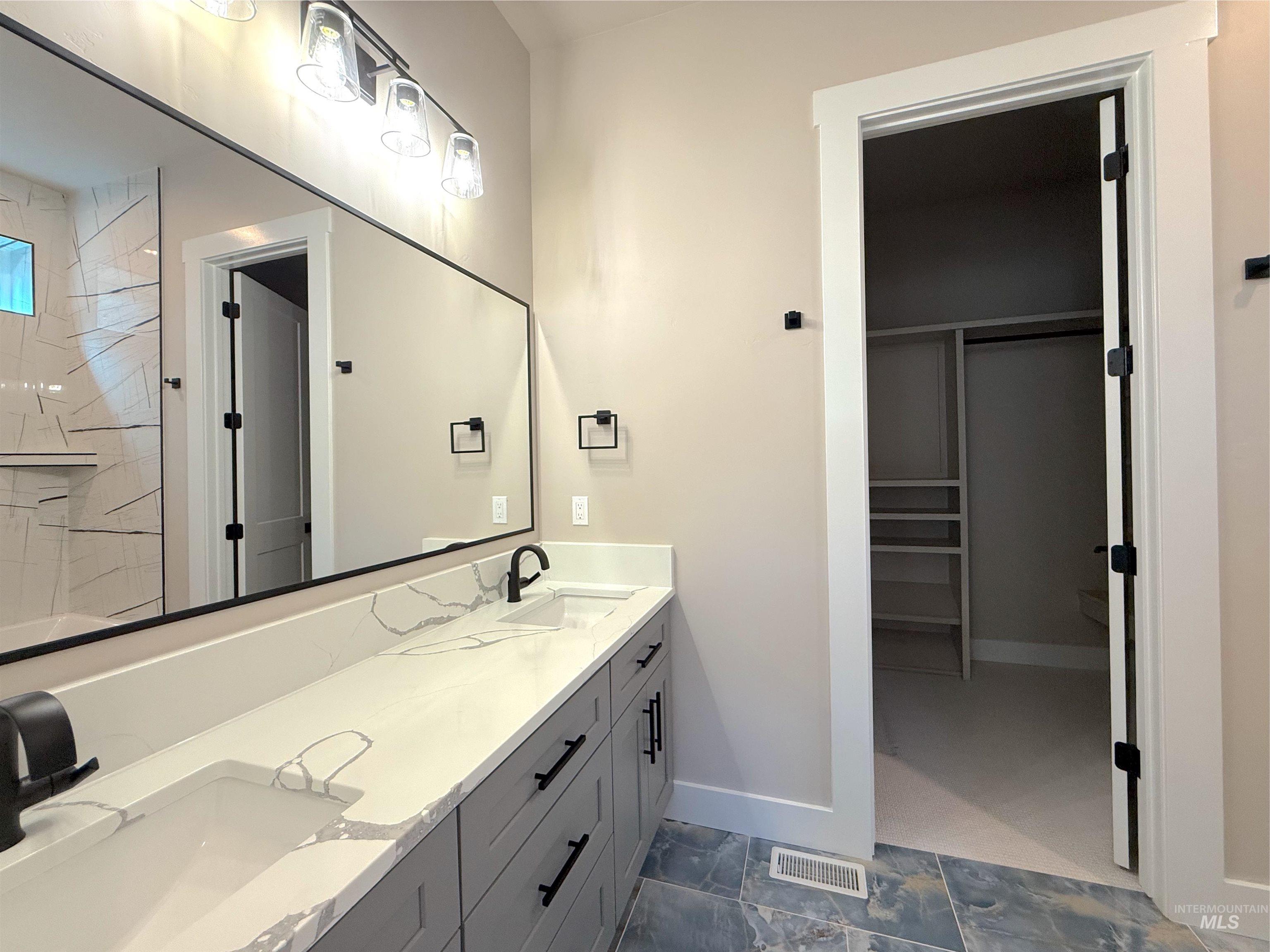 Bathroom featuring a spacious closet, double vanity, and a shower