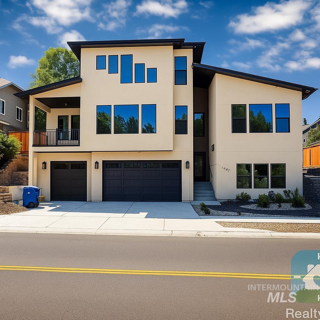 Modern home with stucco siding, a balcony, and driveway