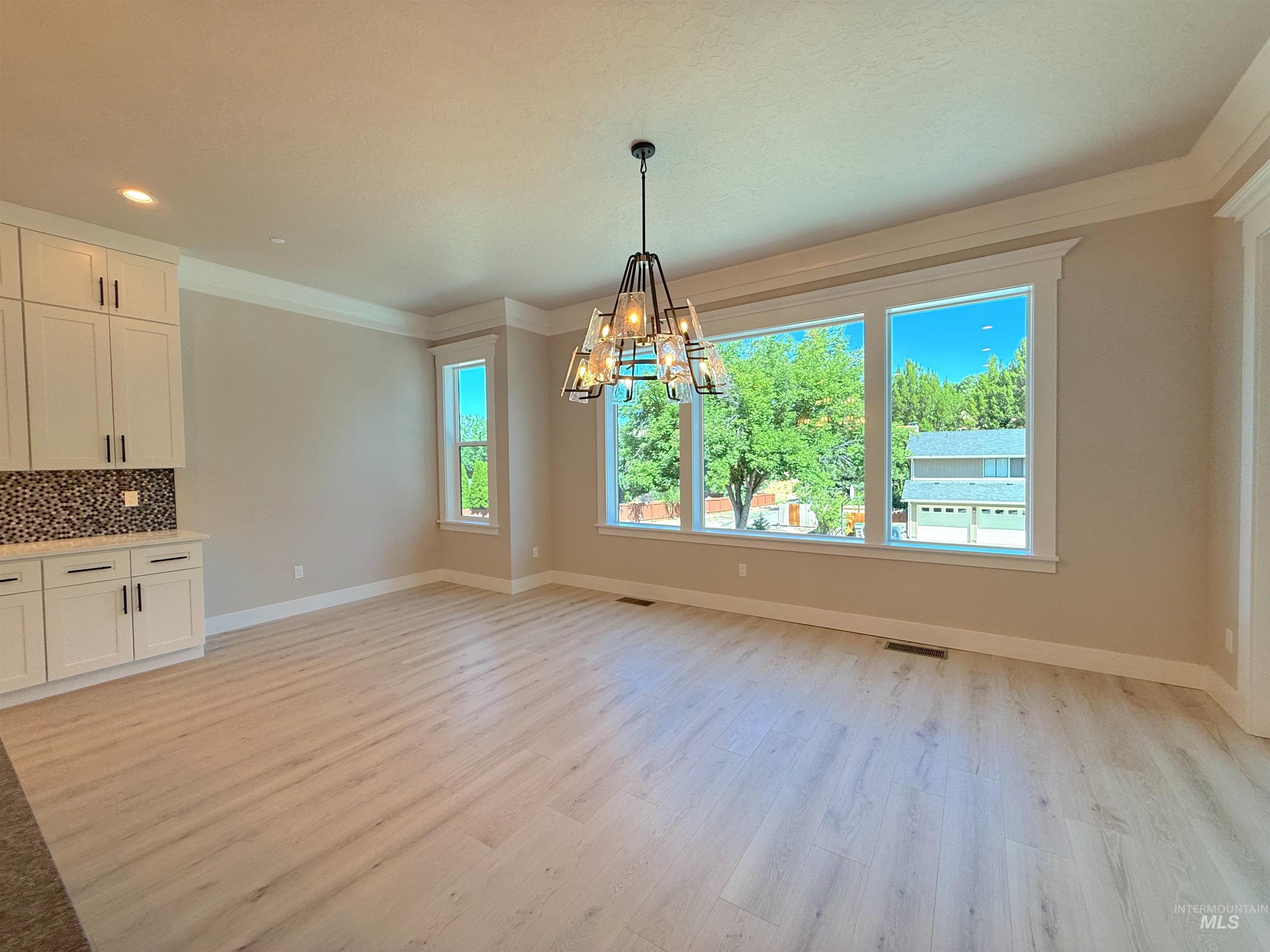 Unfurnished dining area with light wood-type flooring, a chandelier, recessed lighting, and ornamental molding