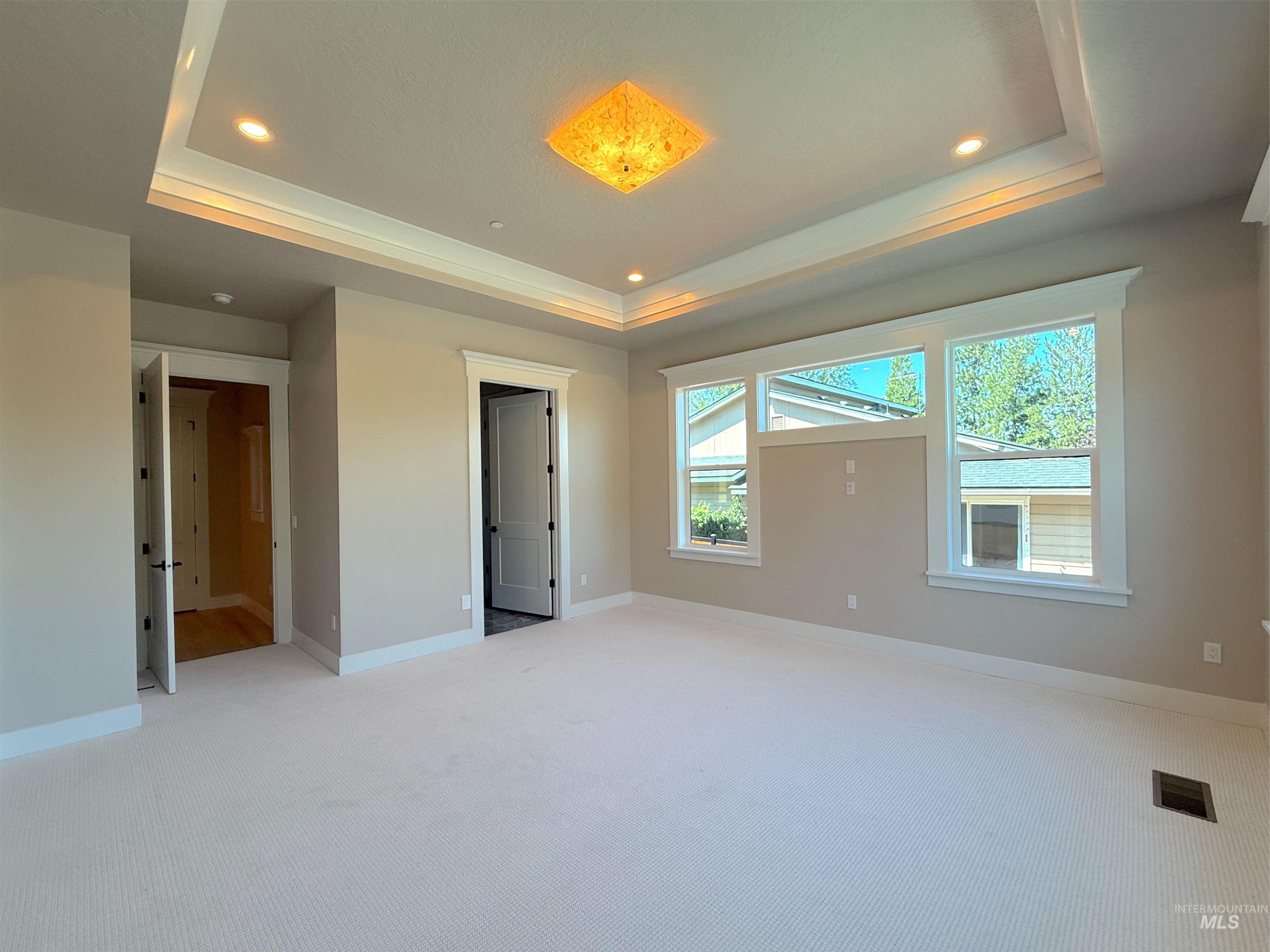 Unfurnished bedroom with a raised ceiling, carpet floors, and recessed lighting