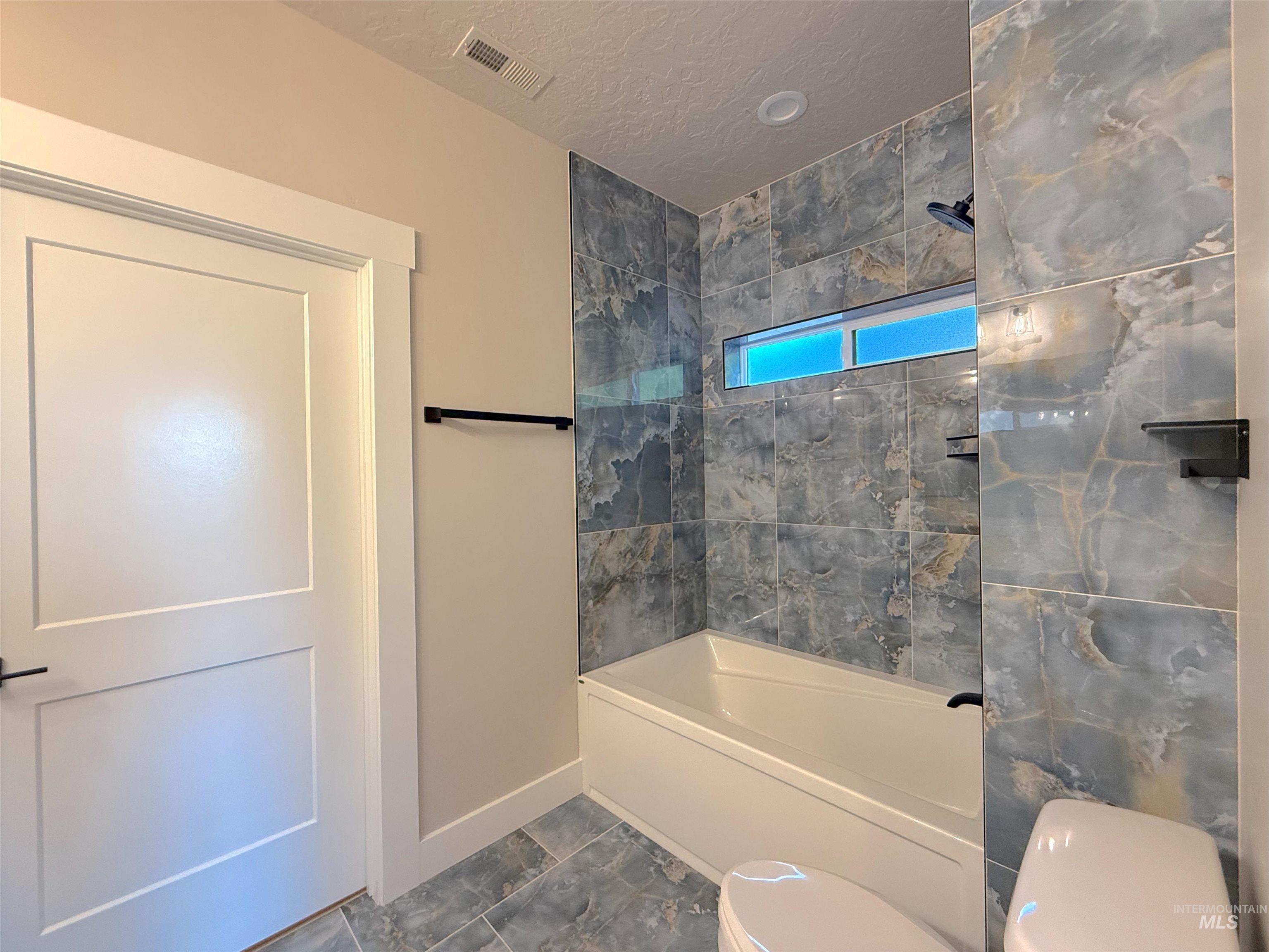 Bathroom with  shower combination and a textured ceiling