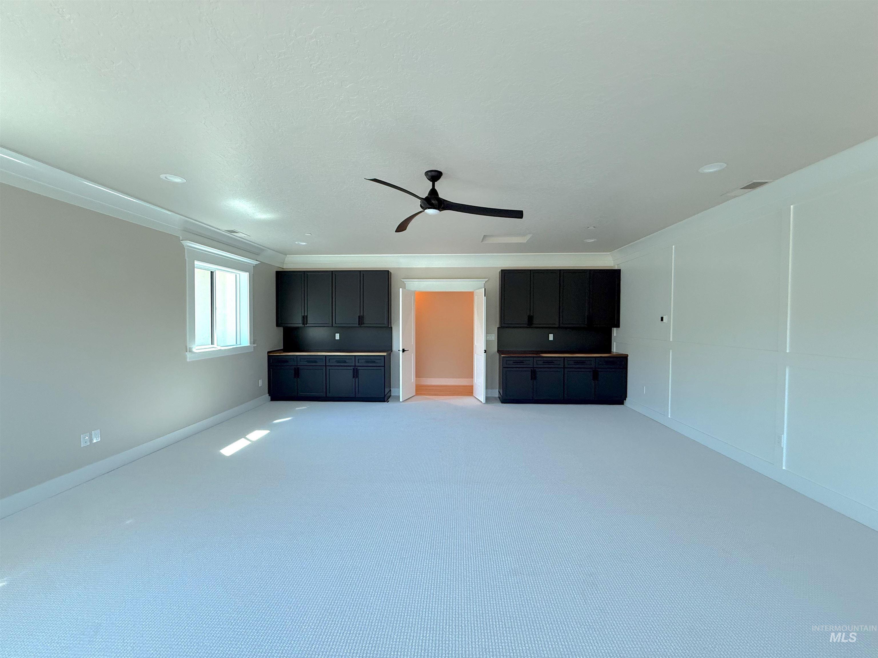Unfurnished living room featuring carpet floors and ceiling fan