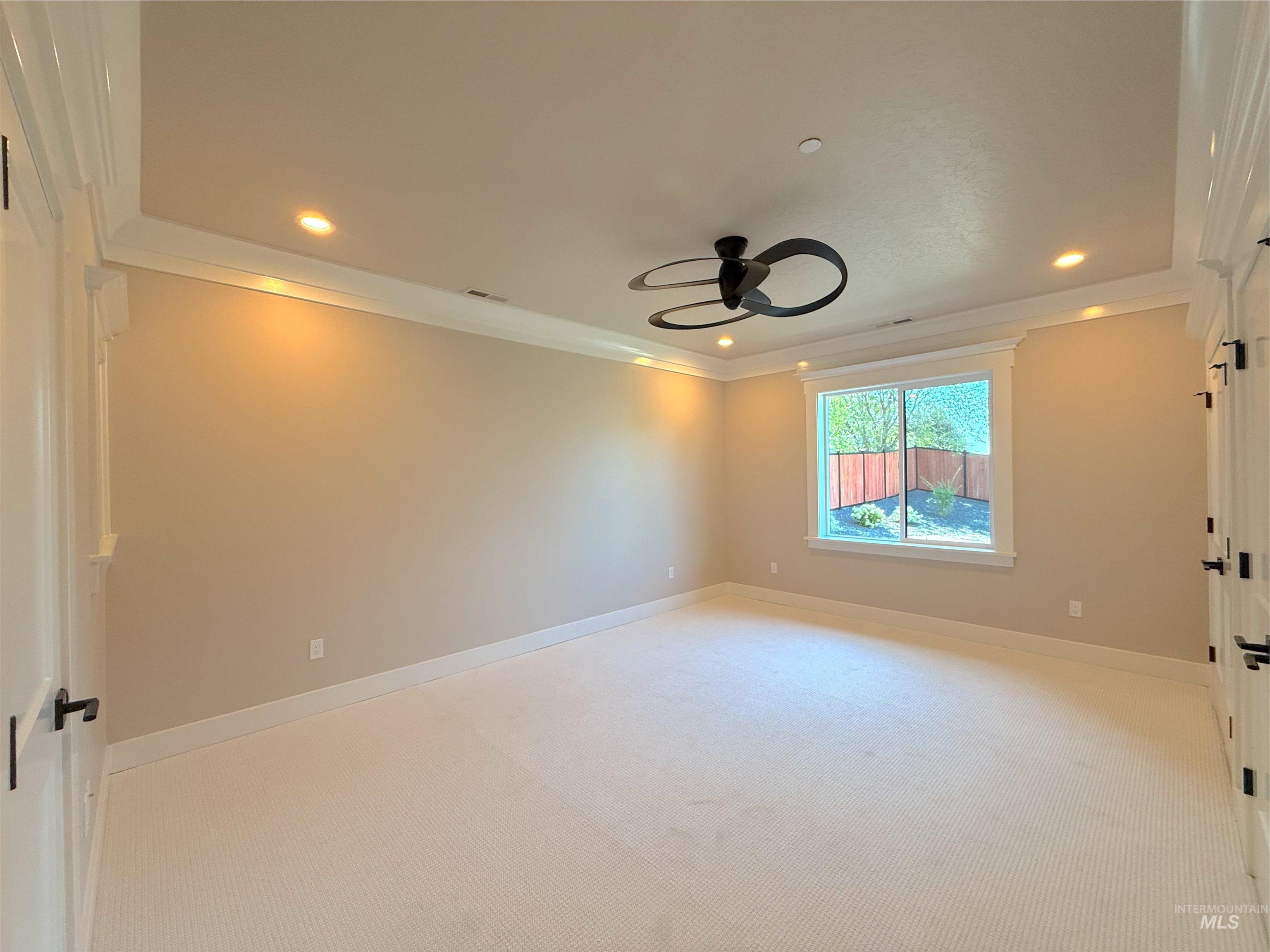 Spare room featuring light carpet, ornamental molding, a ceiling fan, and recessed lighting