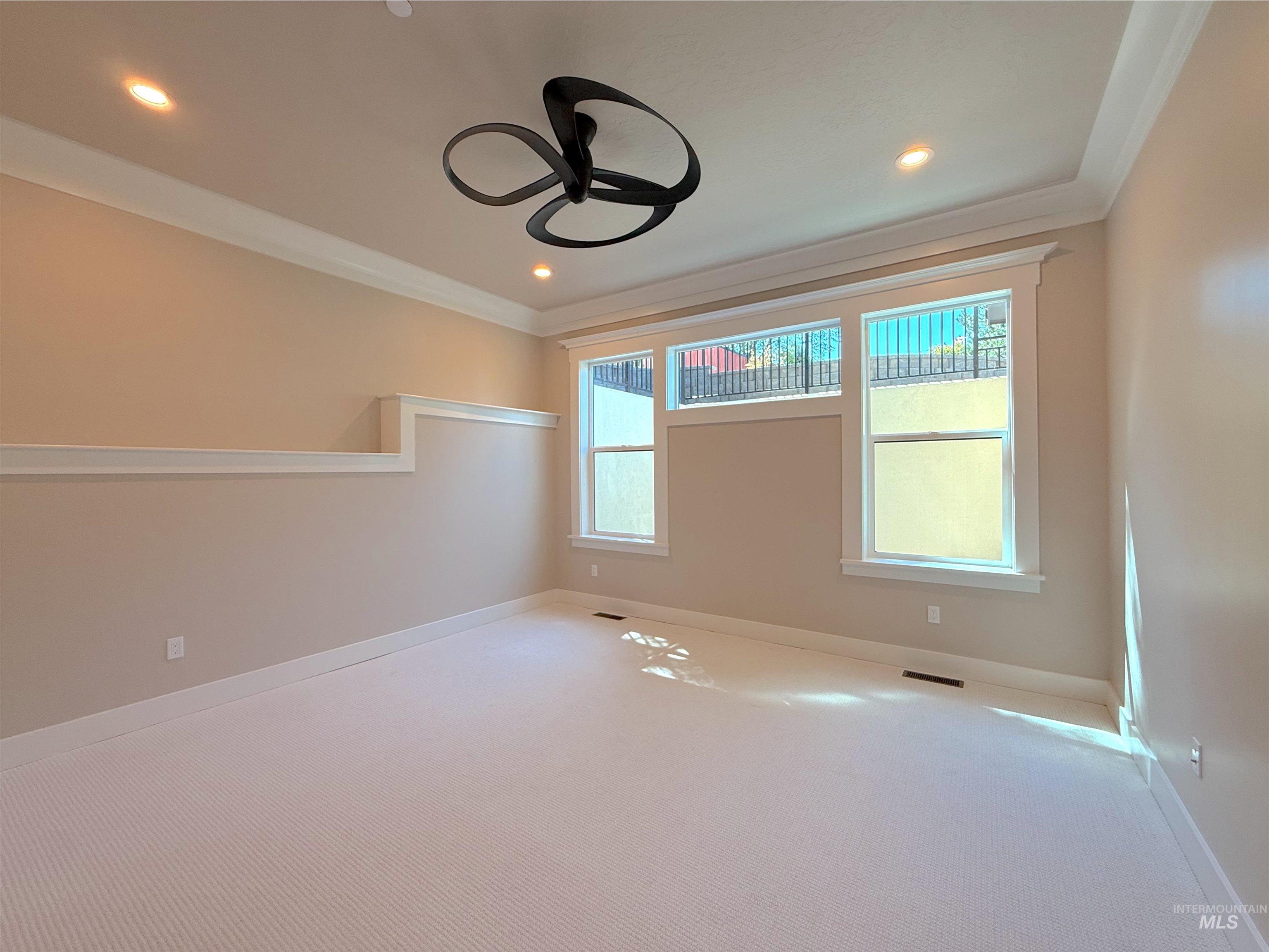 Empty room featuring carpet flooring, healthy amount of natural light, recessed lighting, crown molding, and ceiling fan
