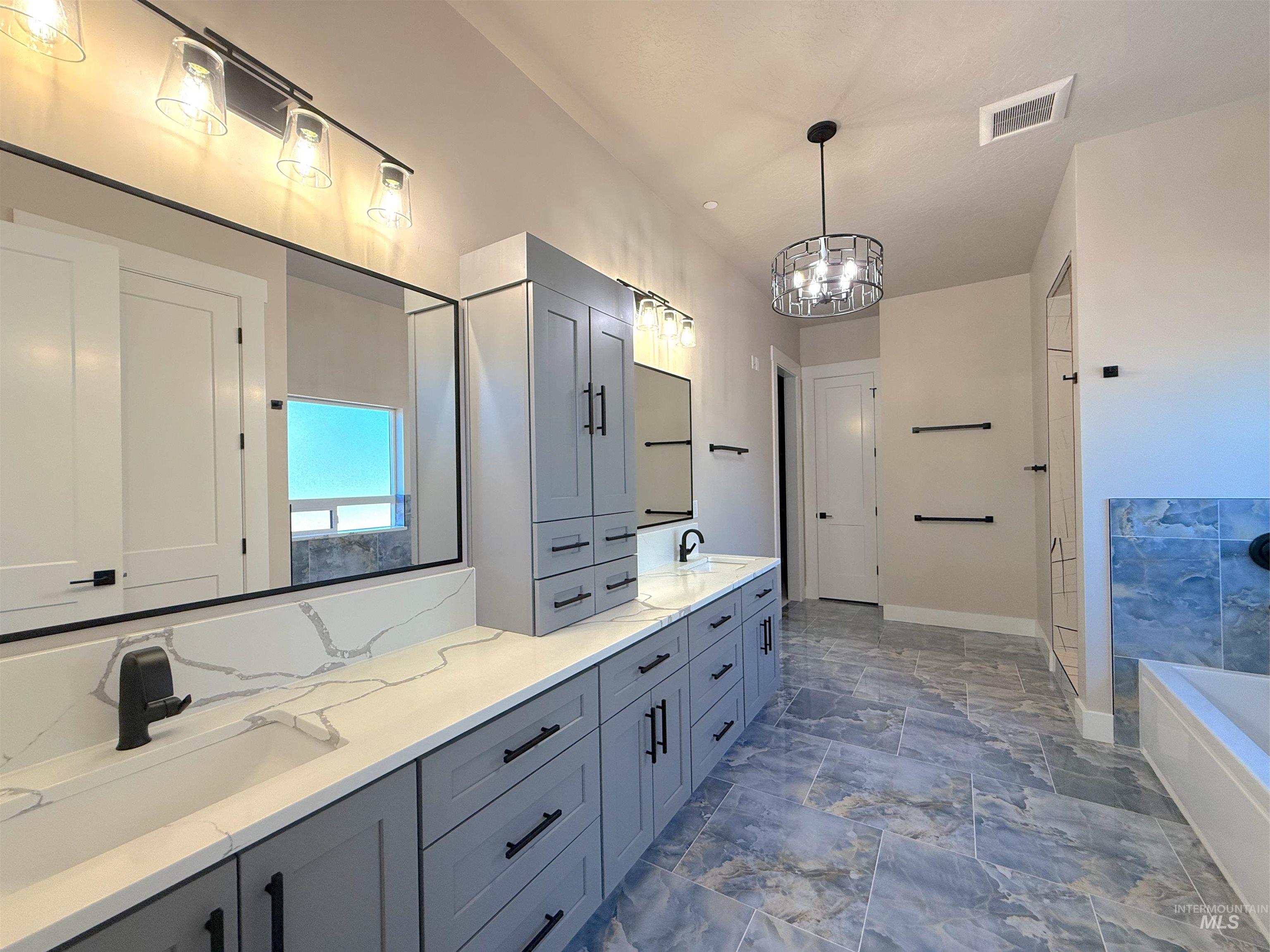 Bathroom featuring double vanity, a garden tub, a chandelier, and a shower
