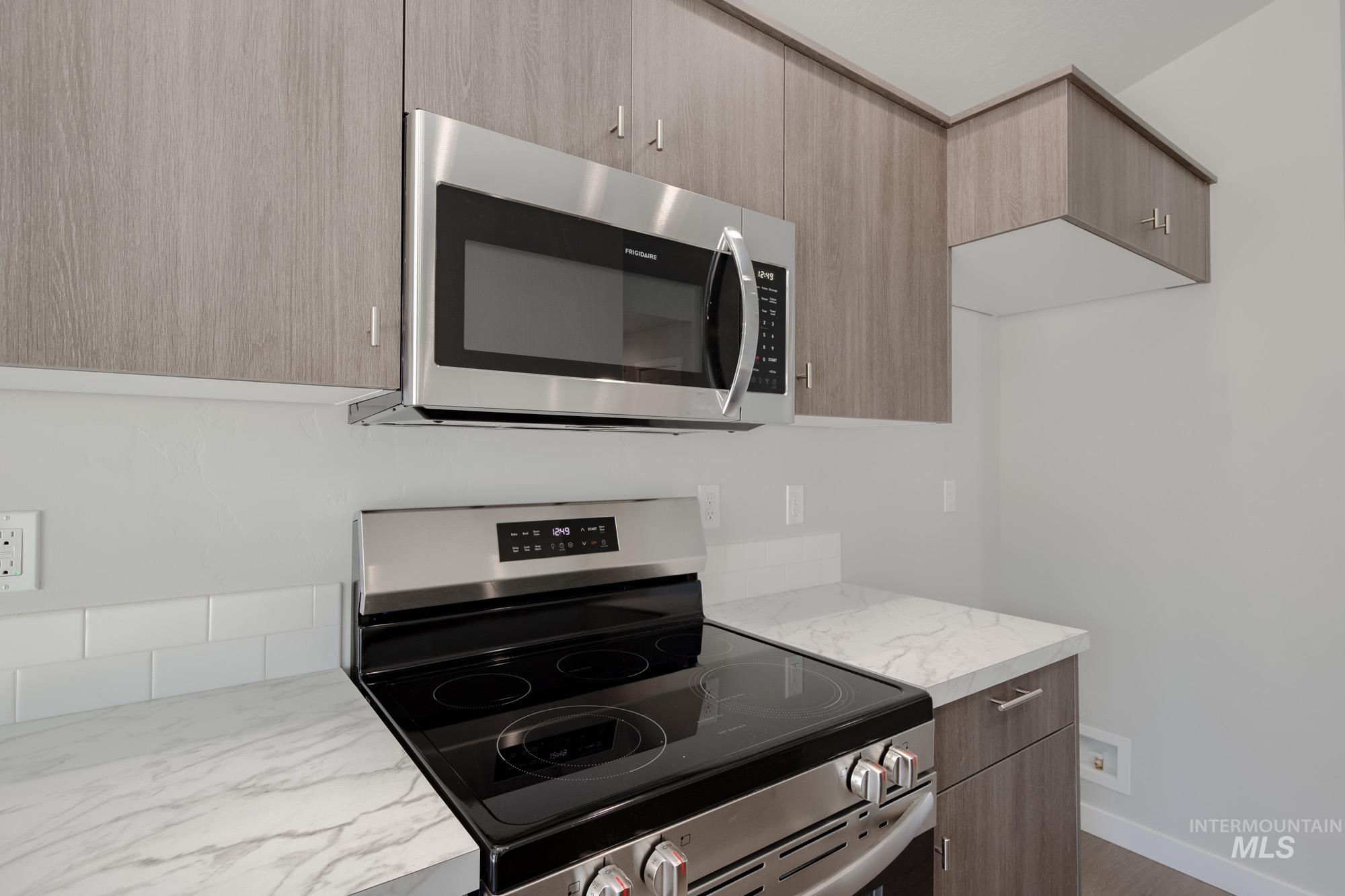 Kitchen with appliances with stainless steel finishes, modern cabinets, and dark wood-style flooring