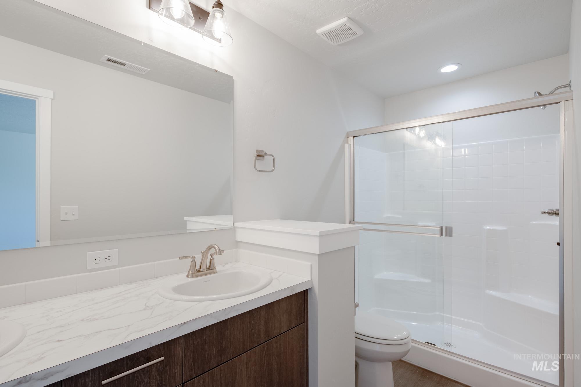 Bathroom with a shower stall, vanity, and recessed lighting