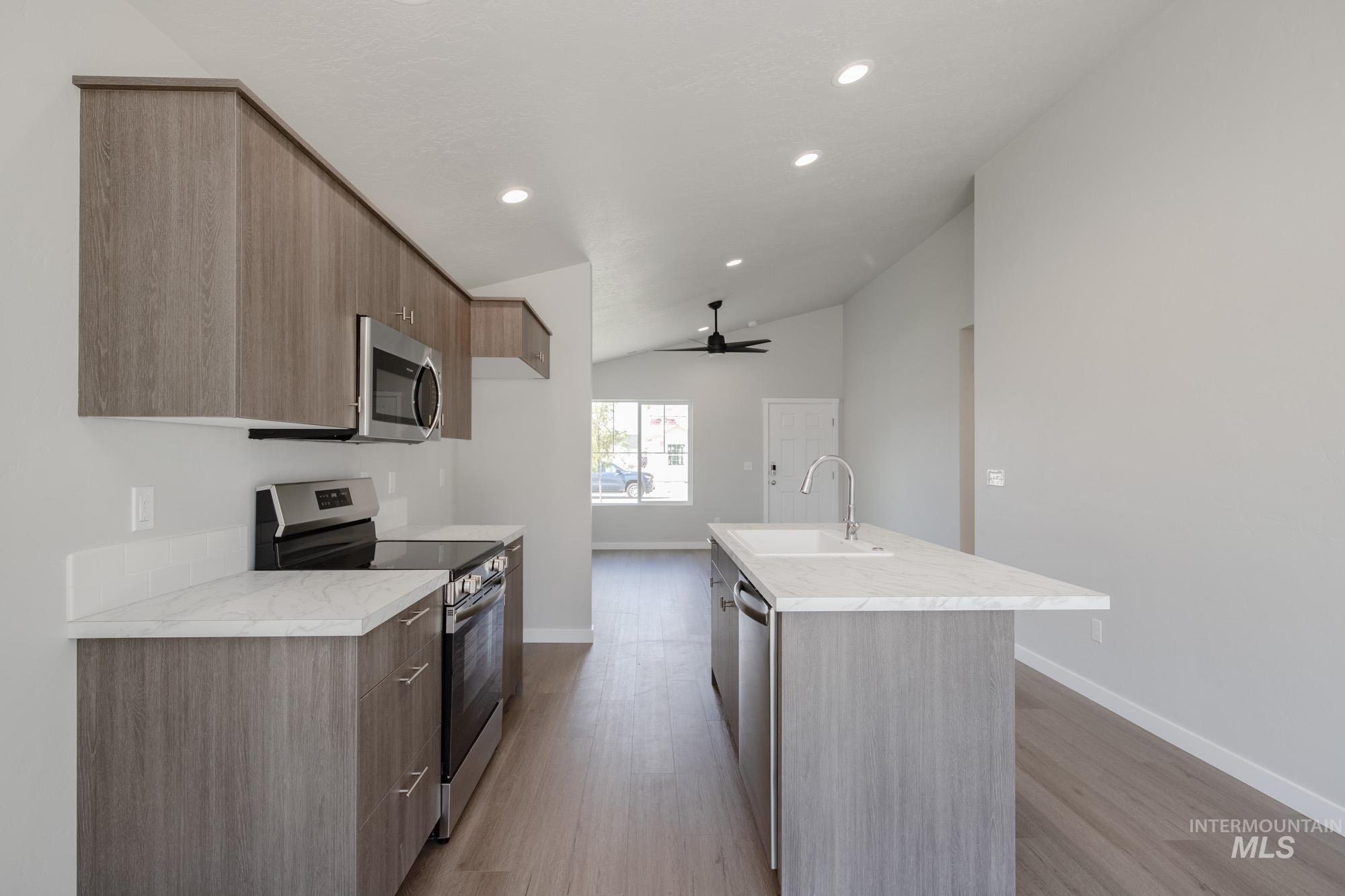 Kitchen featuring modern cabinets, appliances with stainless steel finishes, light wood-style floors, recessed lighting, and lofted ceiling