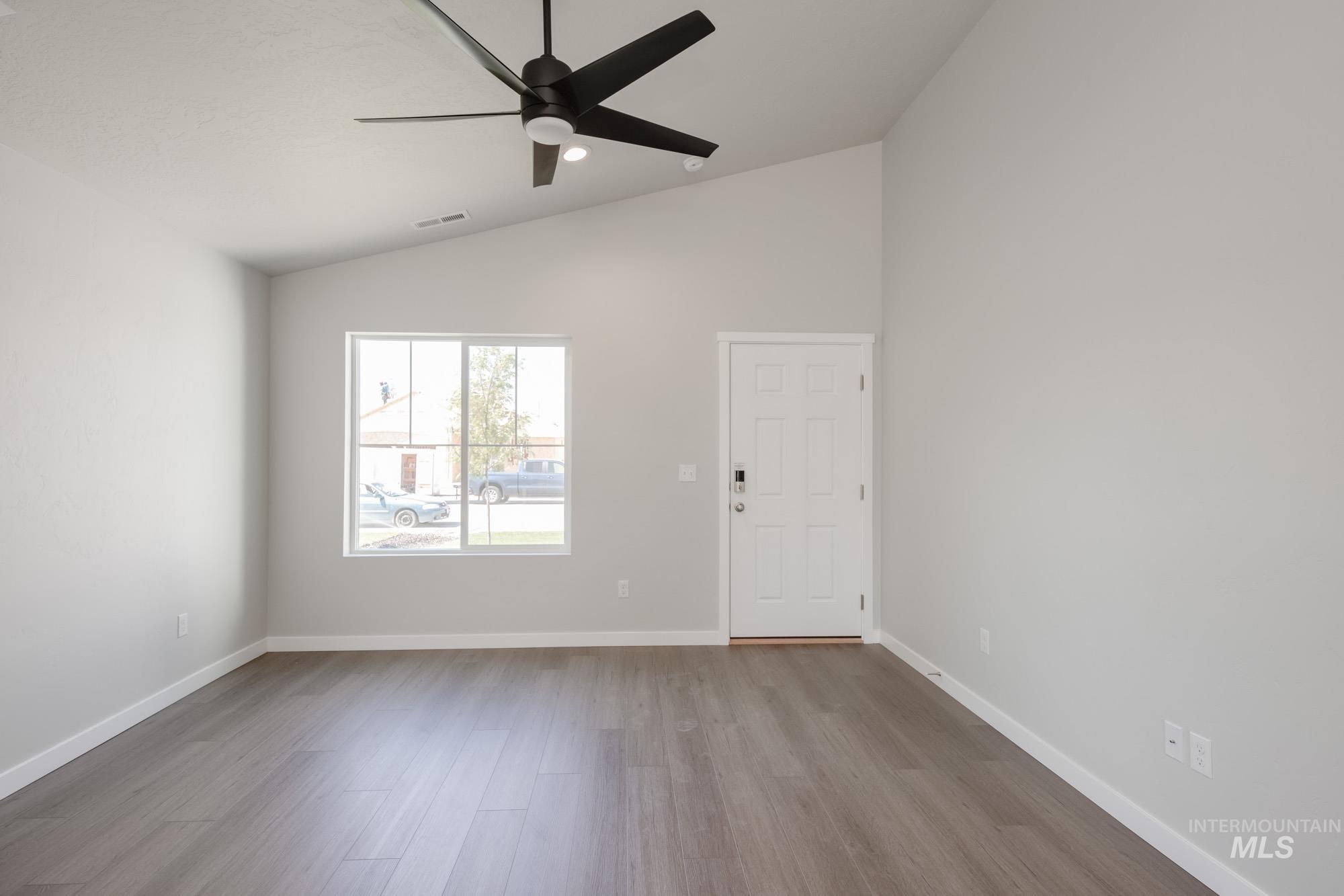 Spare room with lofted ceiling, light wood-style floors, and a ceiling fan