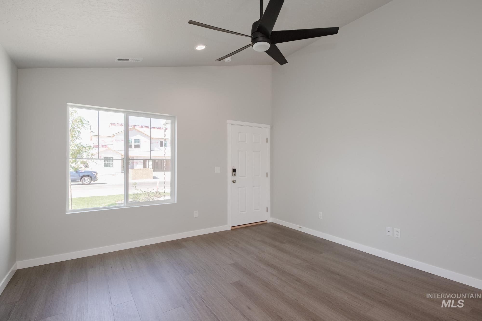 Empty room with wood finished floors, recessed lighting, ceiling fan, and high vaulted ceiling