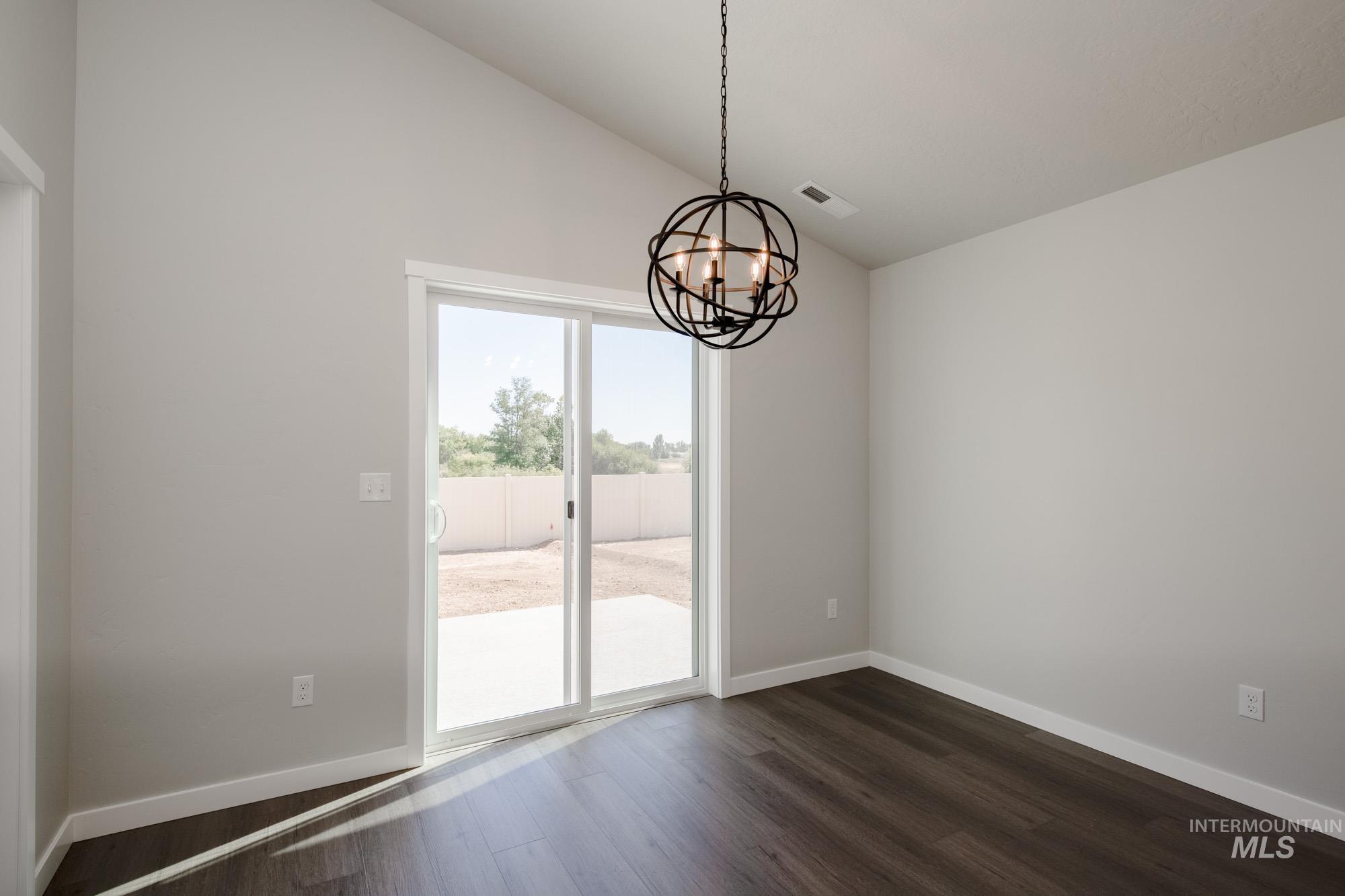 Unfurnished dining area with dark wood-style floors, a chandelier, and high vaulted ceiling