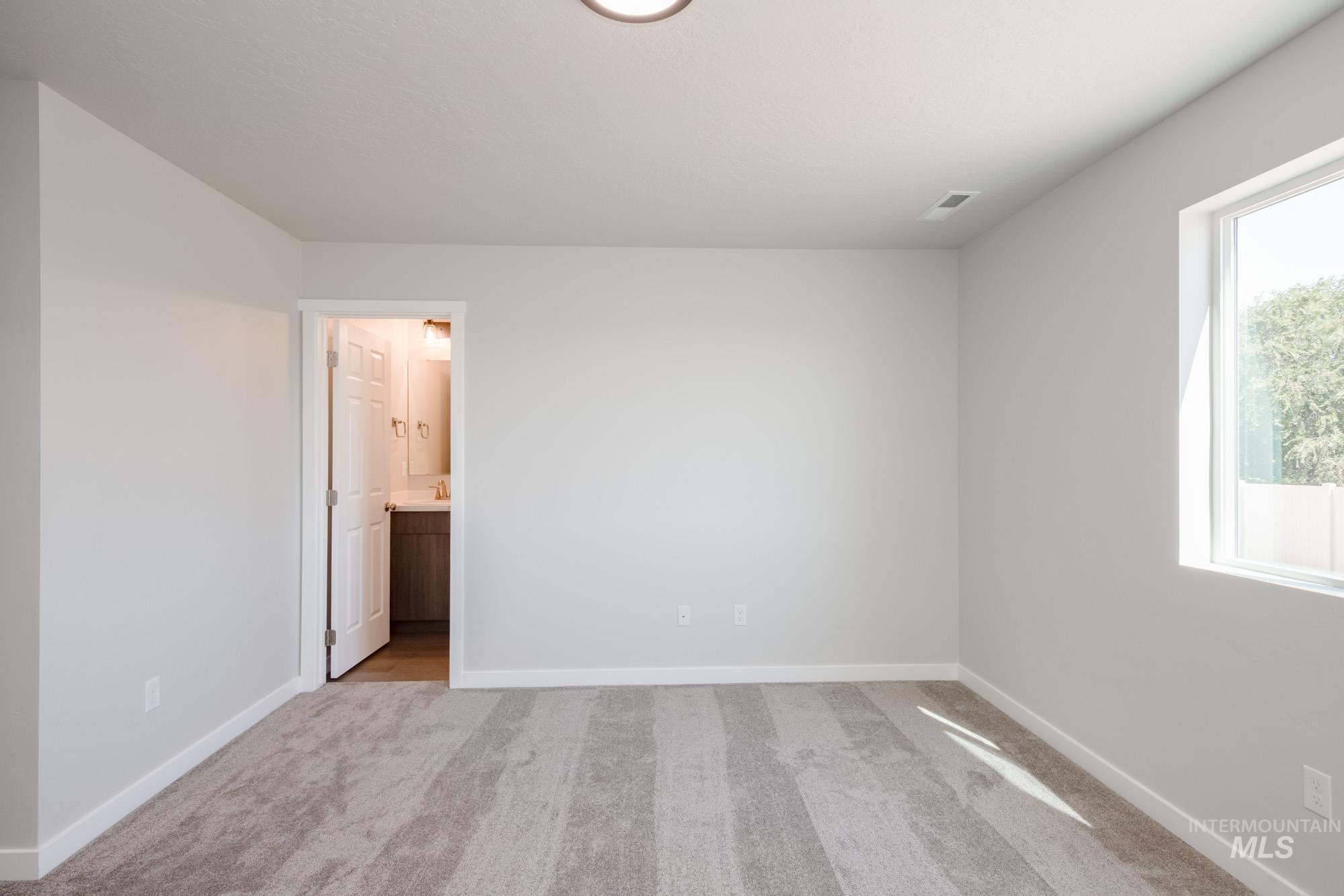 Unfurnished bedroom featuring light carpet and ensuite bath