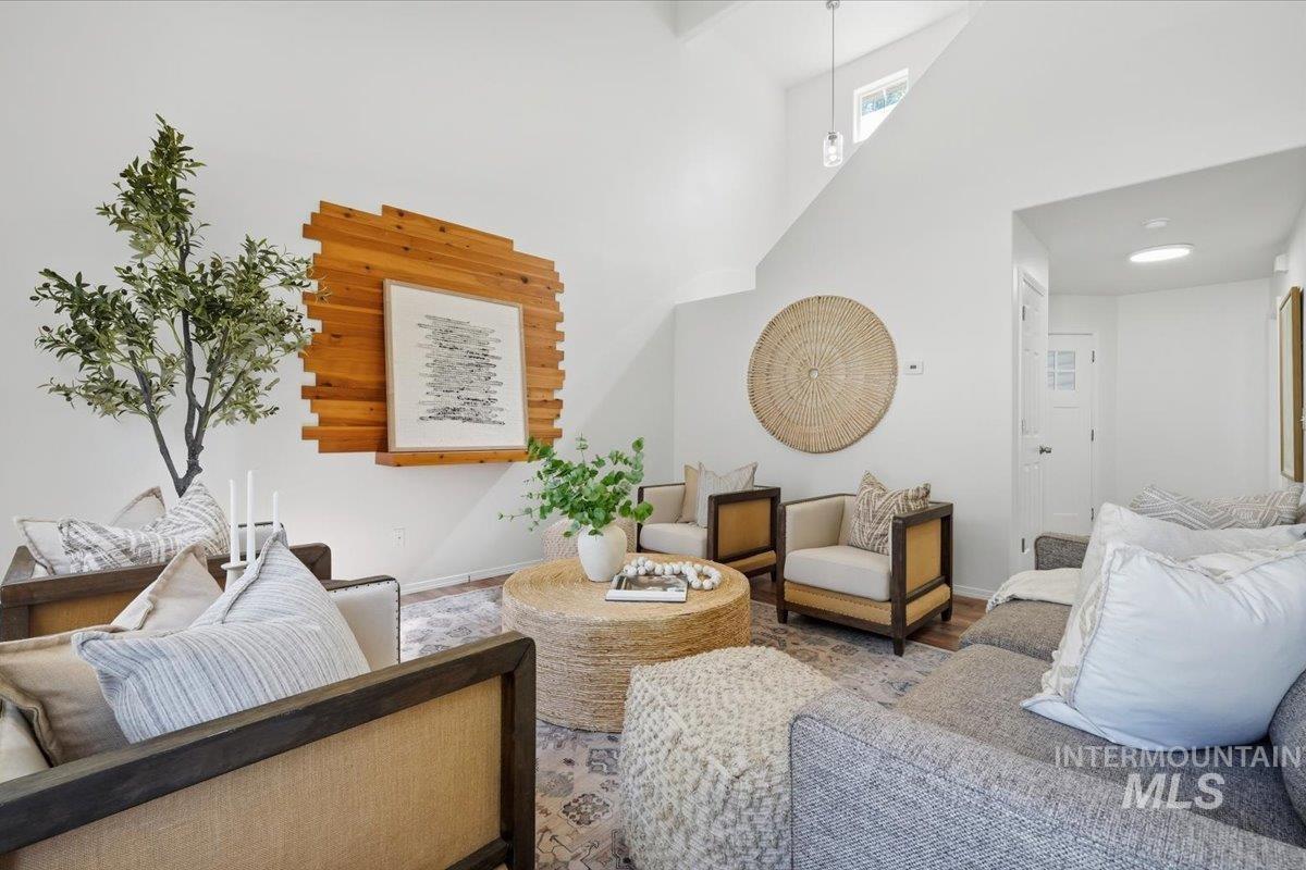 Vaulted ceiling living space featuring a wood-finish accent wall, light-toned wood-finish flooring, recessed lighting, a skylight, and a white paneled door