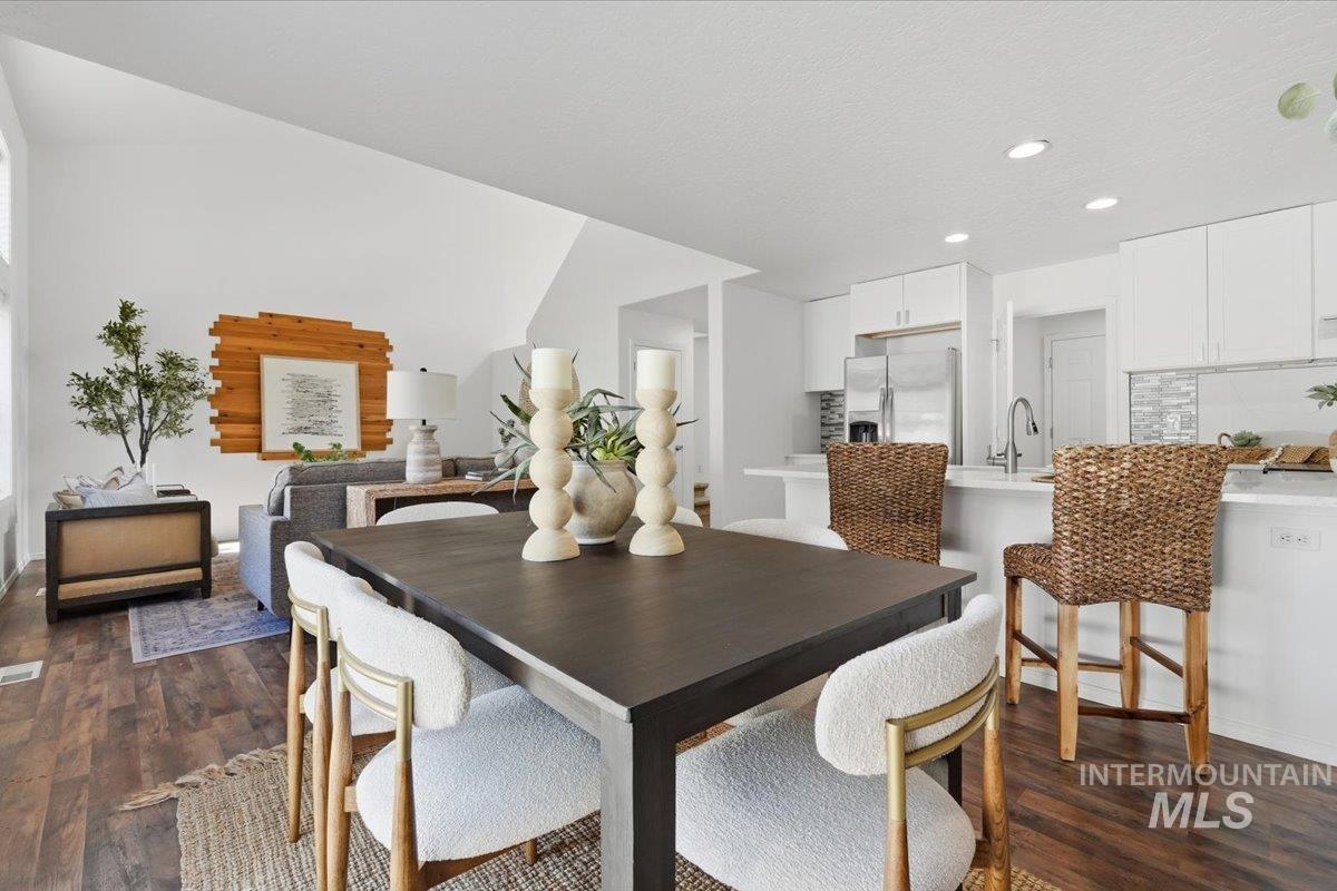 Open-concept dining area featuring wood-finish flooring and a vaulted ceiling