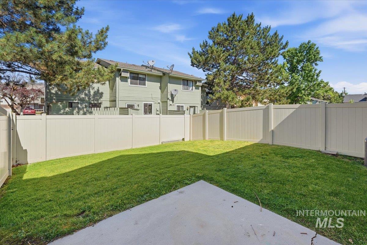 Rear yard with a concrete patio pad, surrounded by a light-toned privacy fence