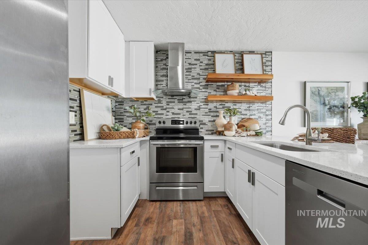 Modern kitchen featuring white cabinetry, wood-finish flooring, stainless steel appliances, a mosaic tile backsplash, and light-toned countertops