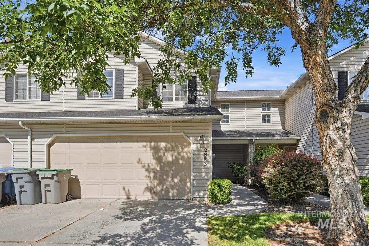 Two-story townhome with light-toned siding, attached garage, and a covered entry
