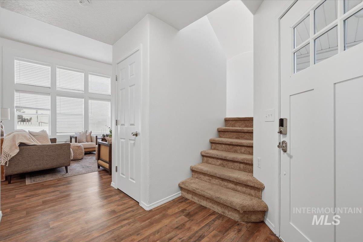 Entryway featuring wood-finish flooring and a staircase with carpeted treads