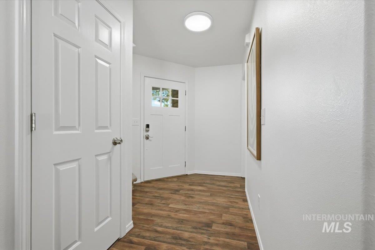 Entryway featuring wood-finish flooring, a six-panel interior door, and a white front door with multiple glass panes