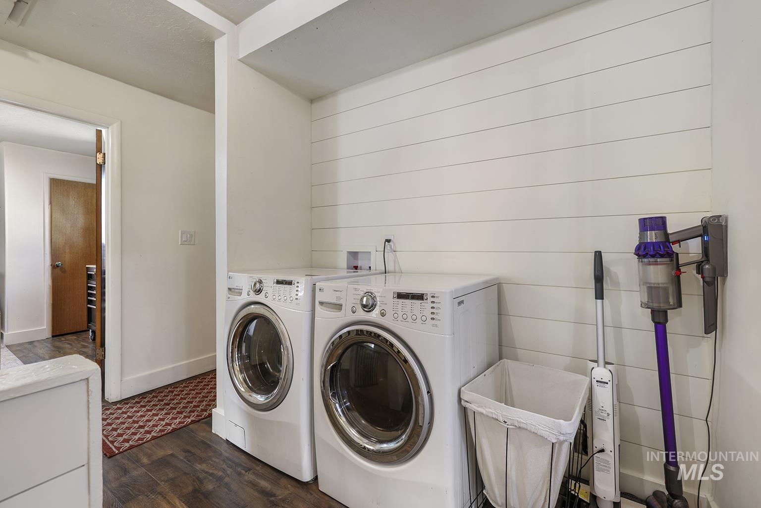 Laundry room with dark wood-style floors and washer and clothes dryer