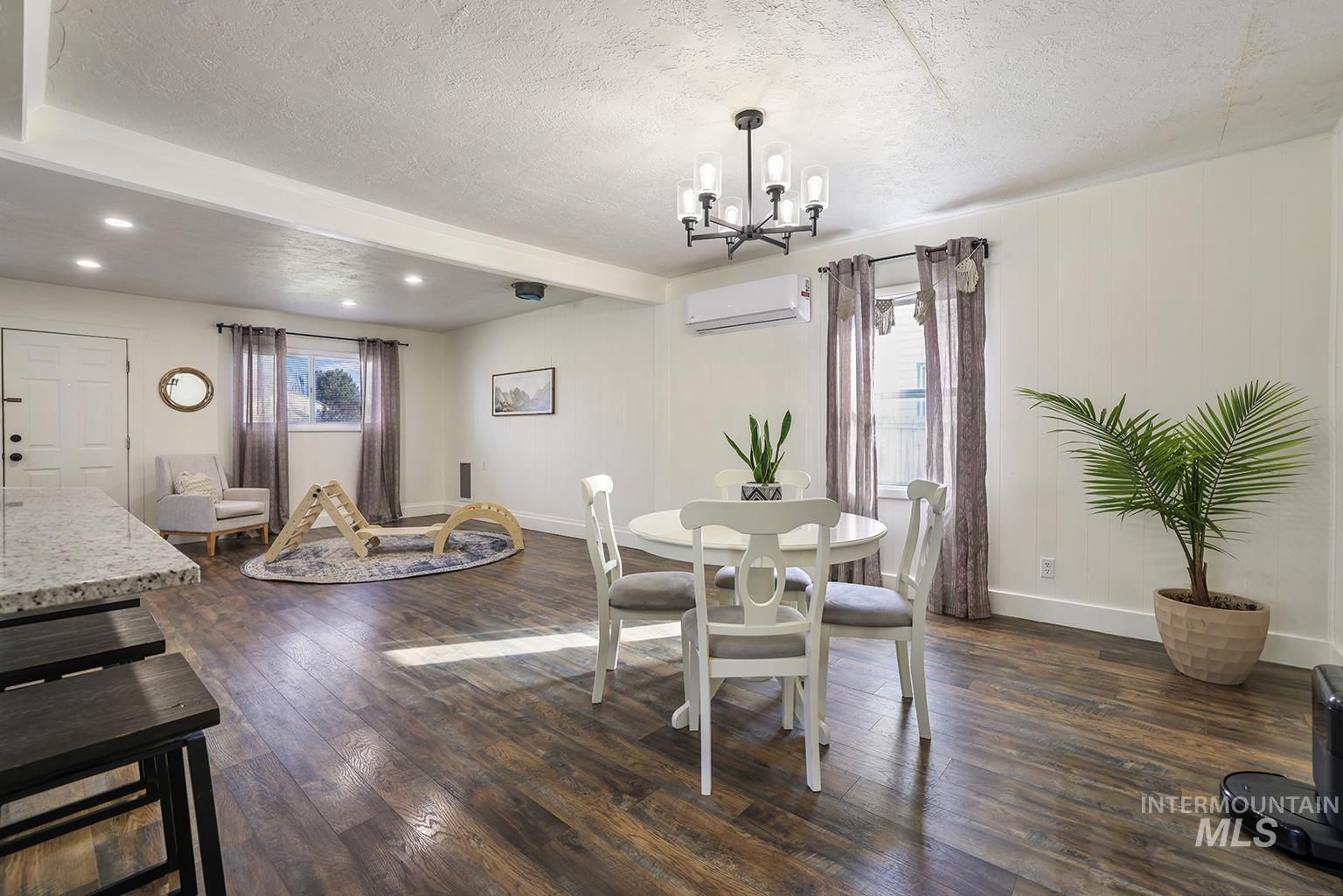 Dining room with dark wood-type flooring, a textured ceiling, a wall mounted air conditioner, a chandelier, and recessed lighting