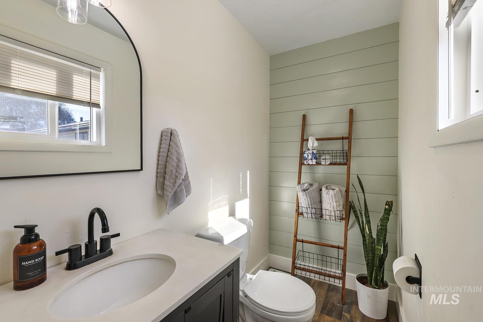 Bathroom with plenty of natural light, vanity, dark wood finished floors, and wooden walls