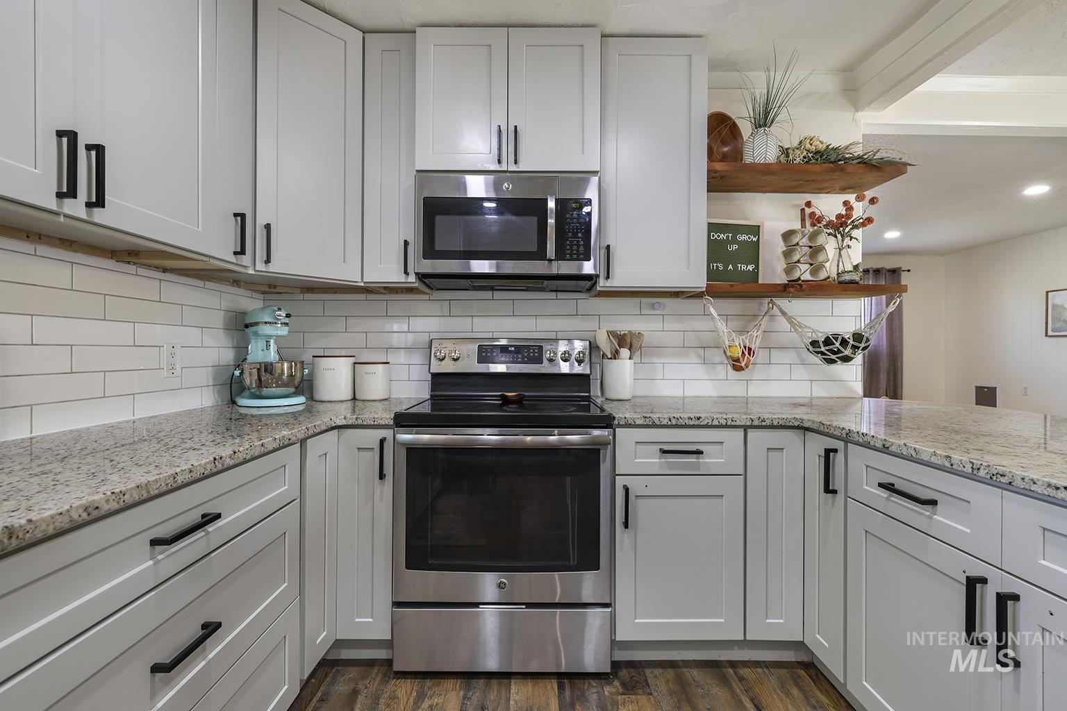 Kitchen with open shelves, appliances with stainless steel finishes, light stone counters, tasteful backsplash, and recessed lighting