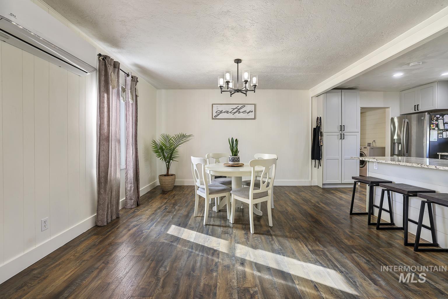Dining room featuring dark wood finished floors, a textured ceiling, and a chandelier