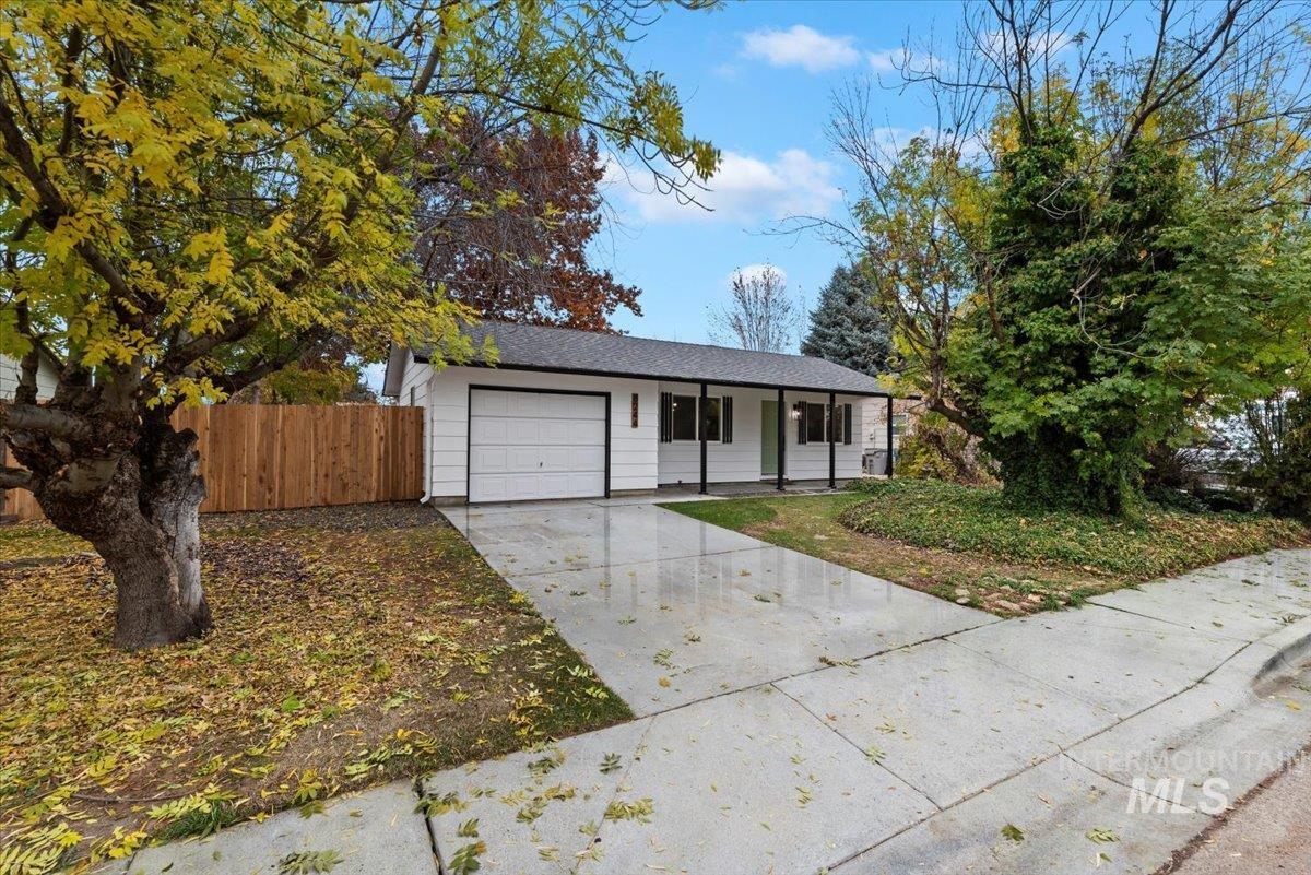 Ranch-style home featuring concrete driveway, covered porch, and a garage