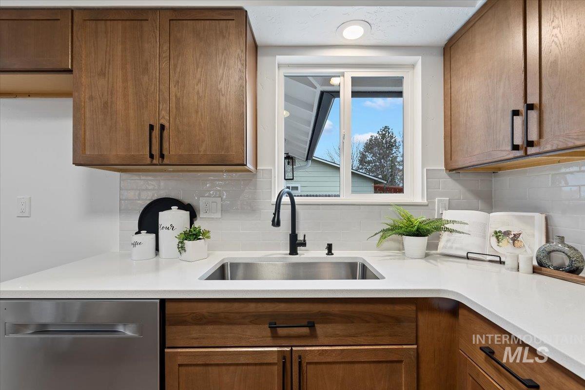 Kitchen featuring brown cabinets, dishwasher, and tasteful backsplash