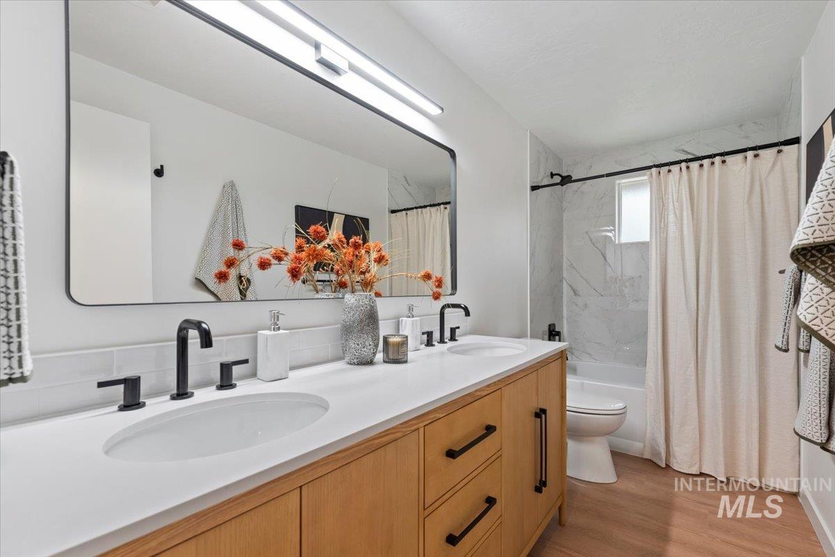 Bathroom featuring double vanity, light wood-style flooring, and shower / bath combination with curtain