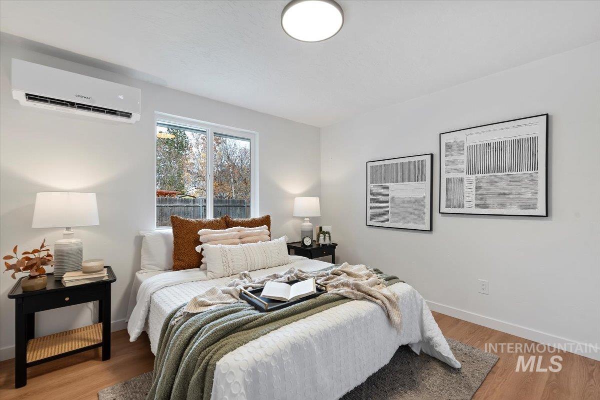 Bedroom featuring light wood-type flooring and a wall mounted AC