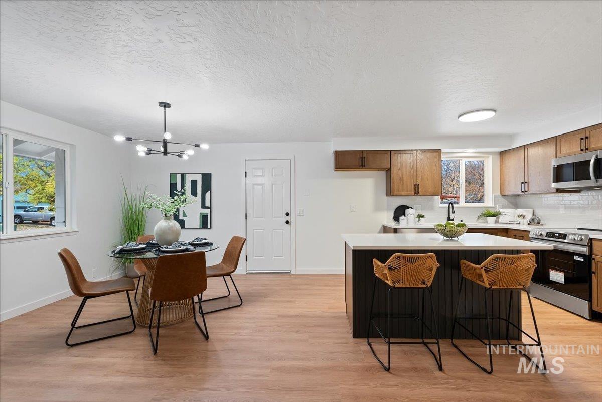 Kitchen with stainless steel appliances, a kitchen island, a kitchen breakfast bar, light wood-style flooring, and a textured ceiling