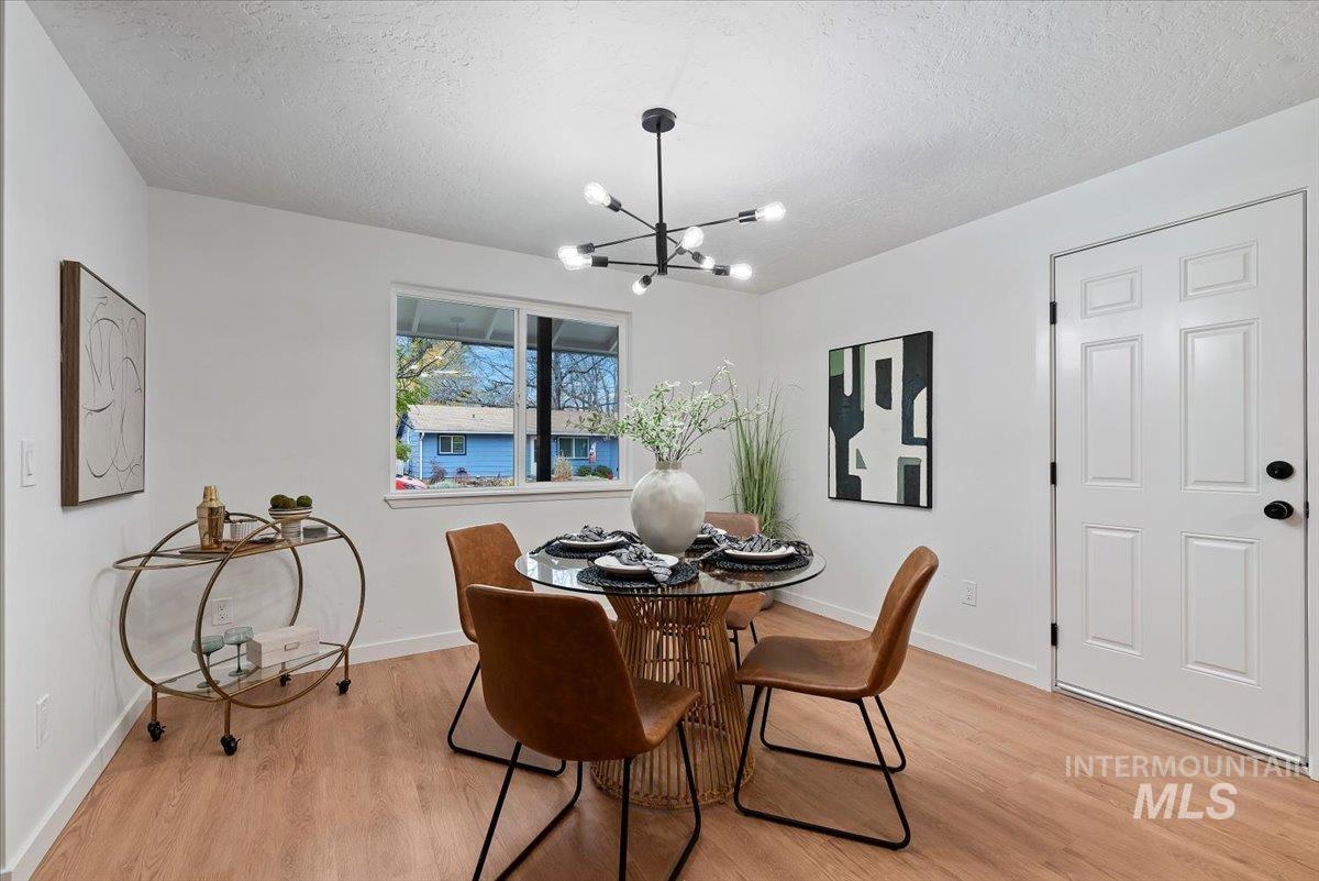 Dining room with light wood-style flooring, a chandelier, and a textured ceiling