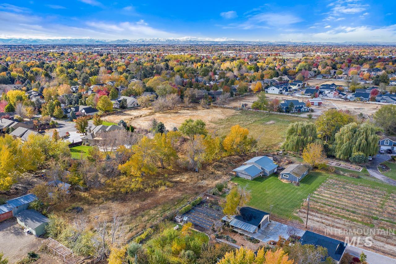 Expansive aerial view showcasing a diverse landscape with residential areas, open fields, and mature trees