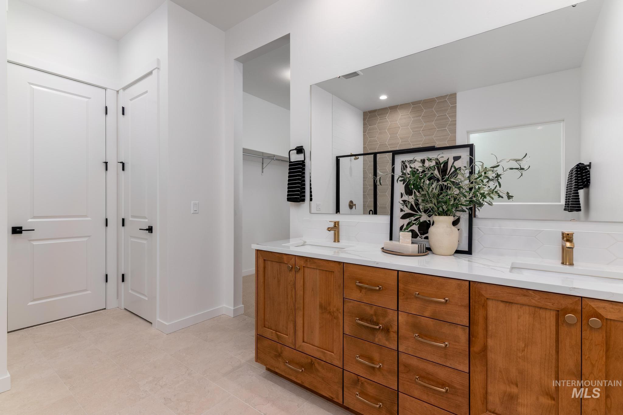 Full bath featuring a stall shower, double vanity, a spacious closet, and recessed lighting