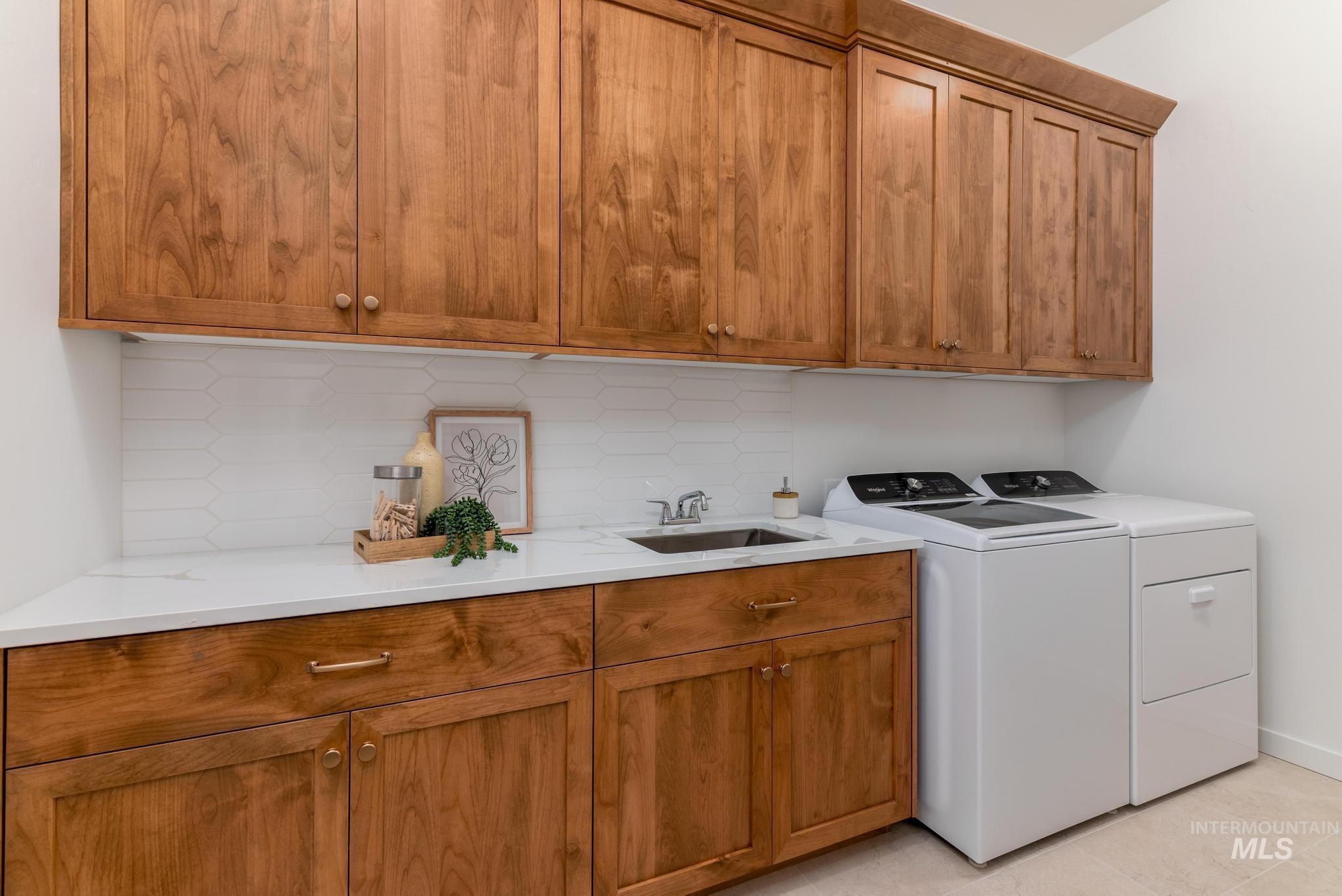 Laundry room featuring cabinet space, washing machine and dryer, and light tile patterned floors