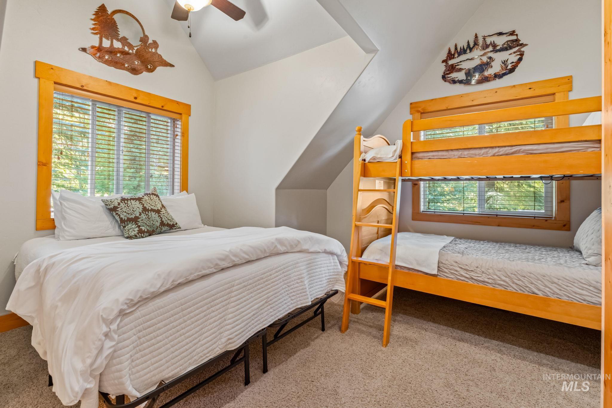 Bedroom featuring lofted ceiling, multiple windows, carpet, and a ceiling fan