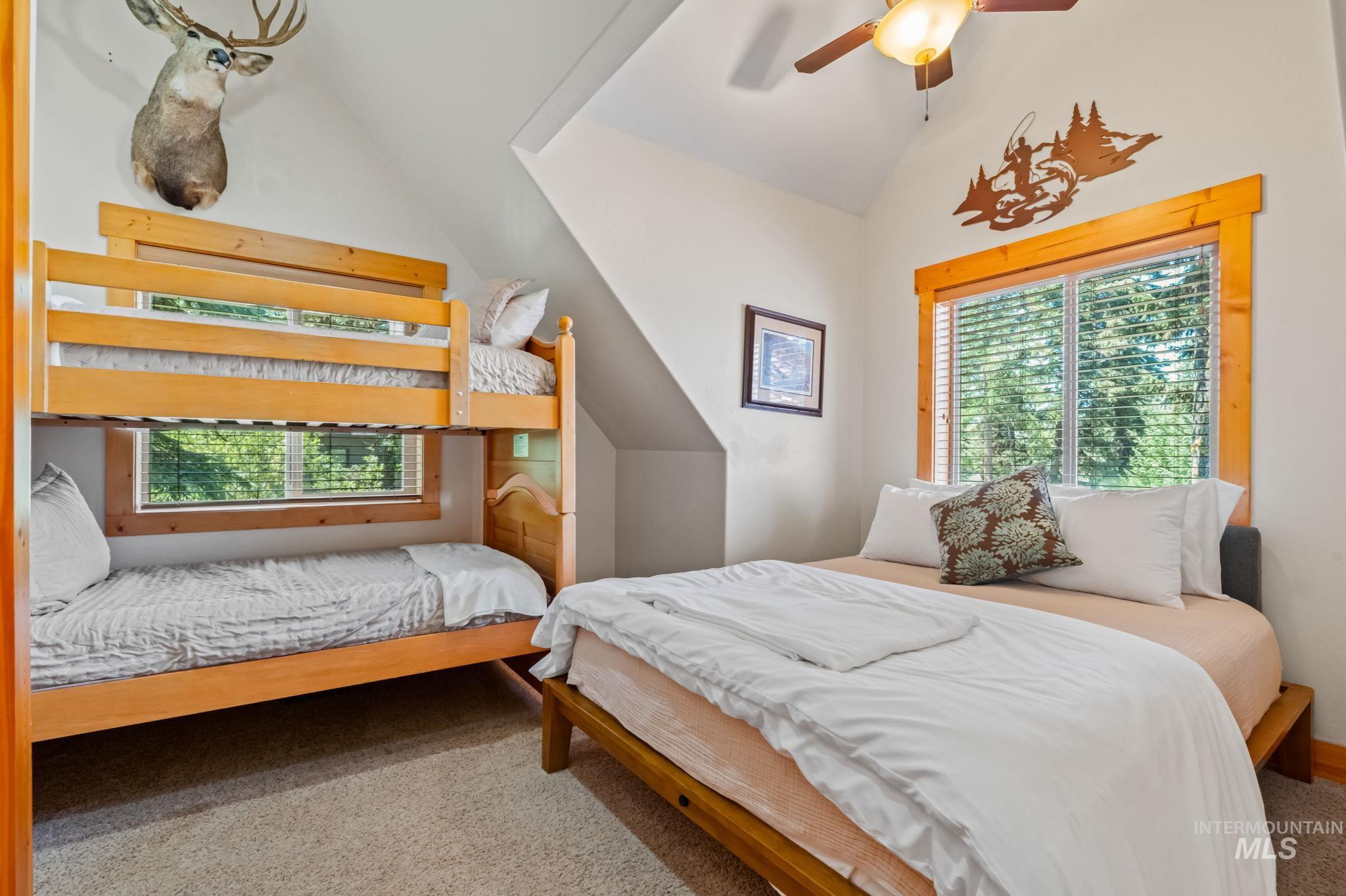 Bedroom featuring lofted ceiling, carpet flooring, and a ceiling fan