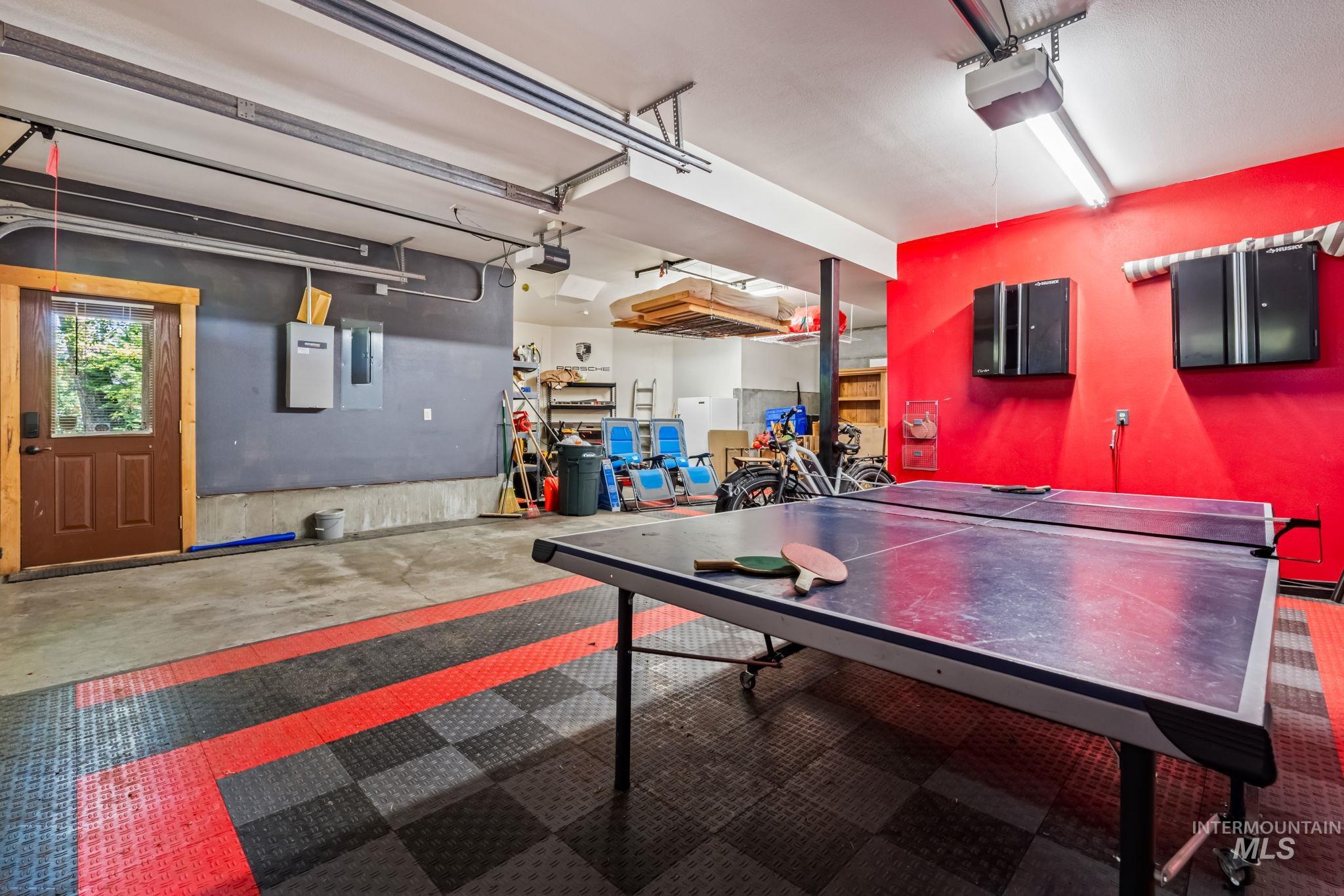 Game room with concrete flooring, a garage, and electric panel