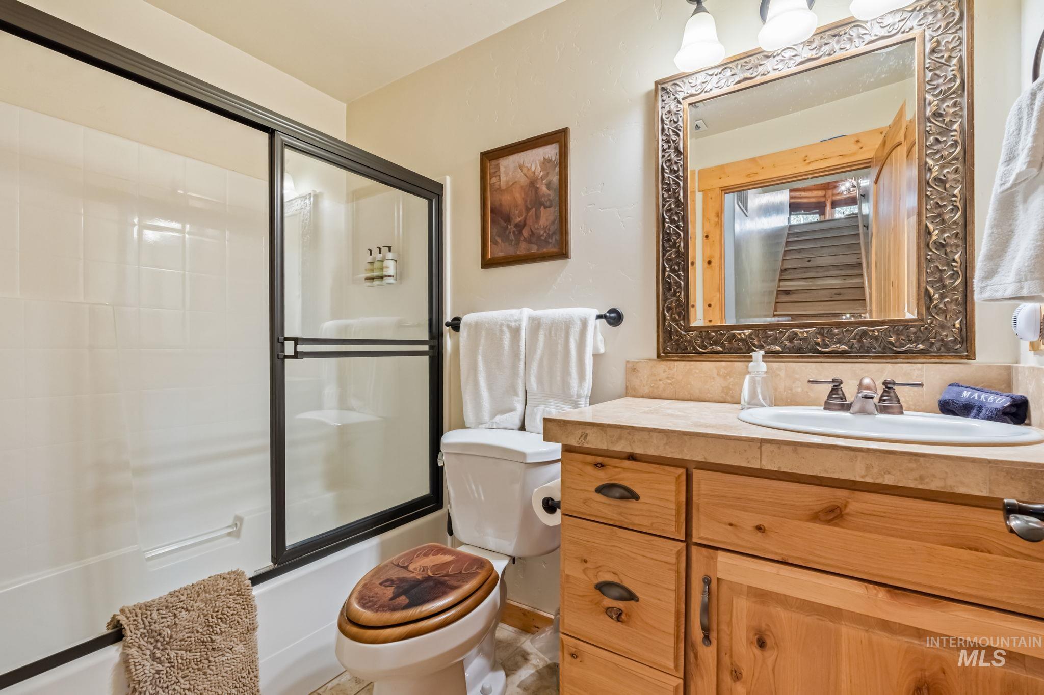 Bathroom with vanity and combined bath / shower with glass door