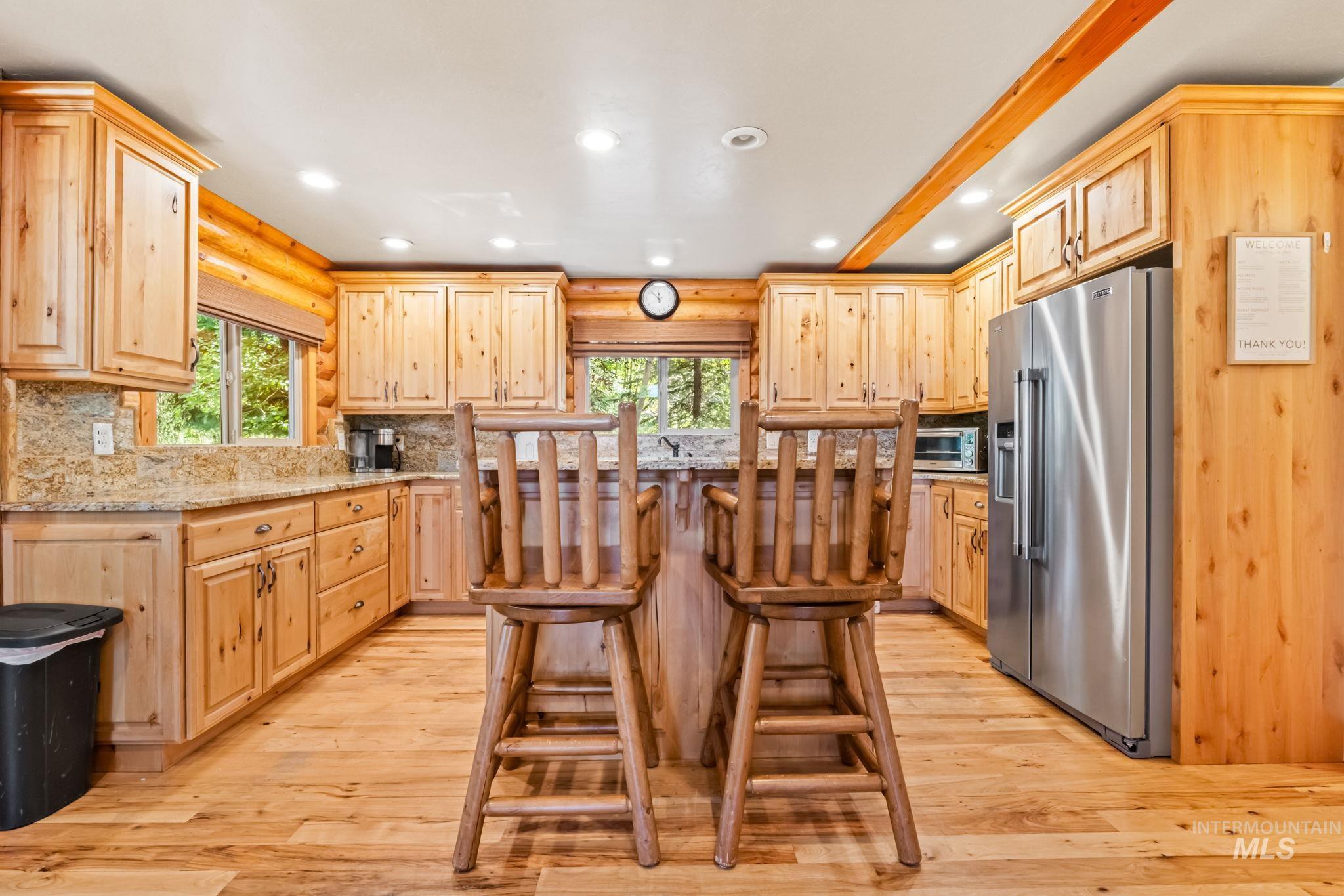 Kitchen with recessed lighting, a breakfast bar area, high end fridge, light brown cabinetry, and decorative backsplash