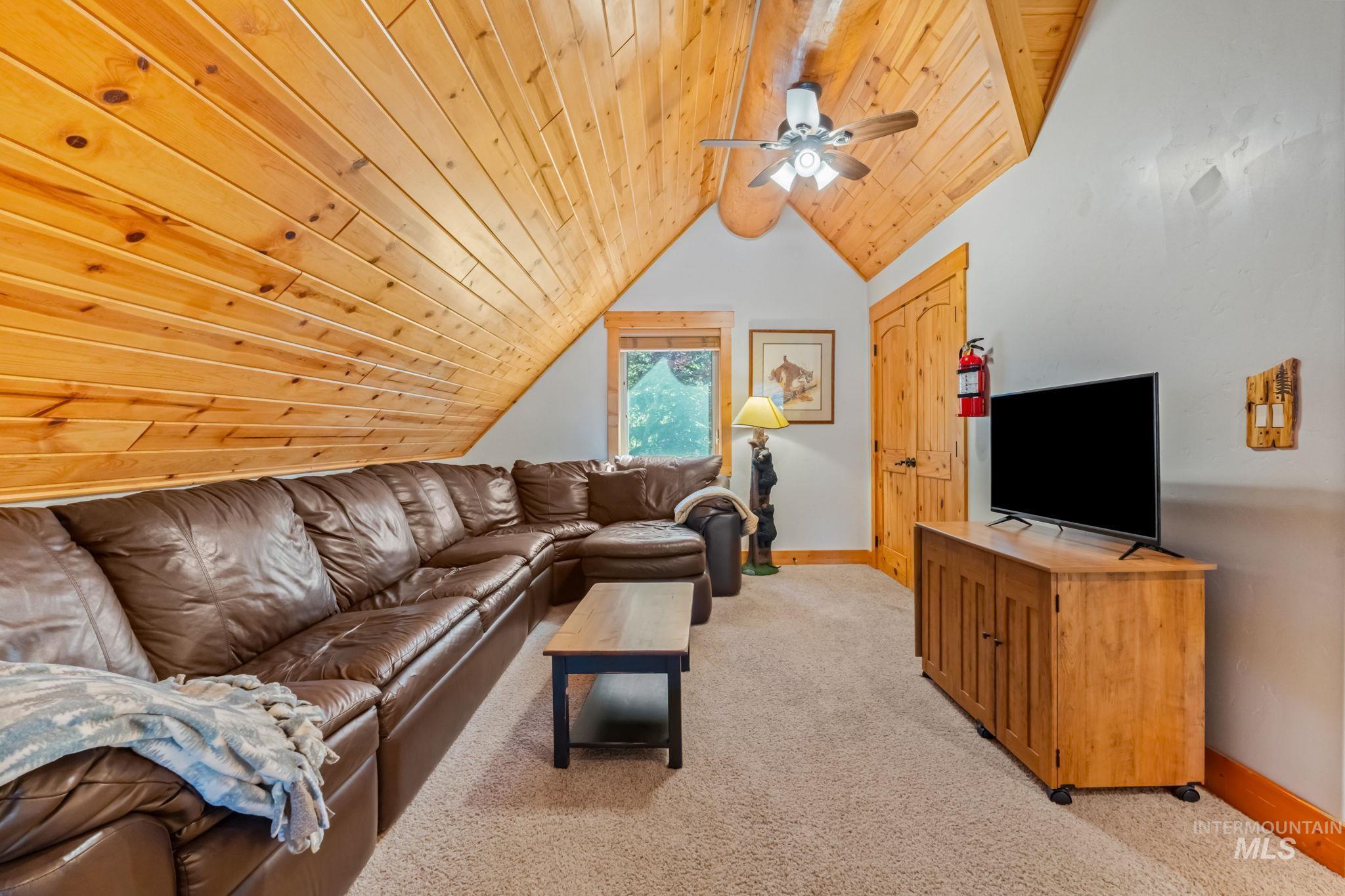 Living room with light colored carpet, wood ceiling, and ceiling fan