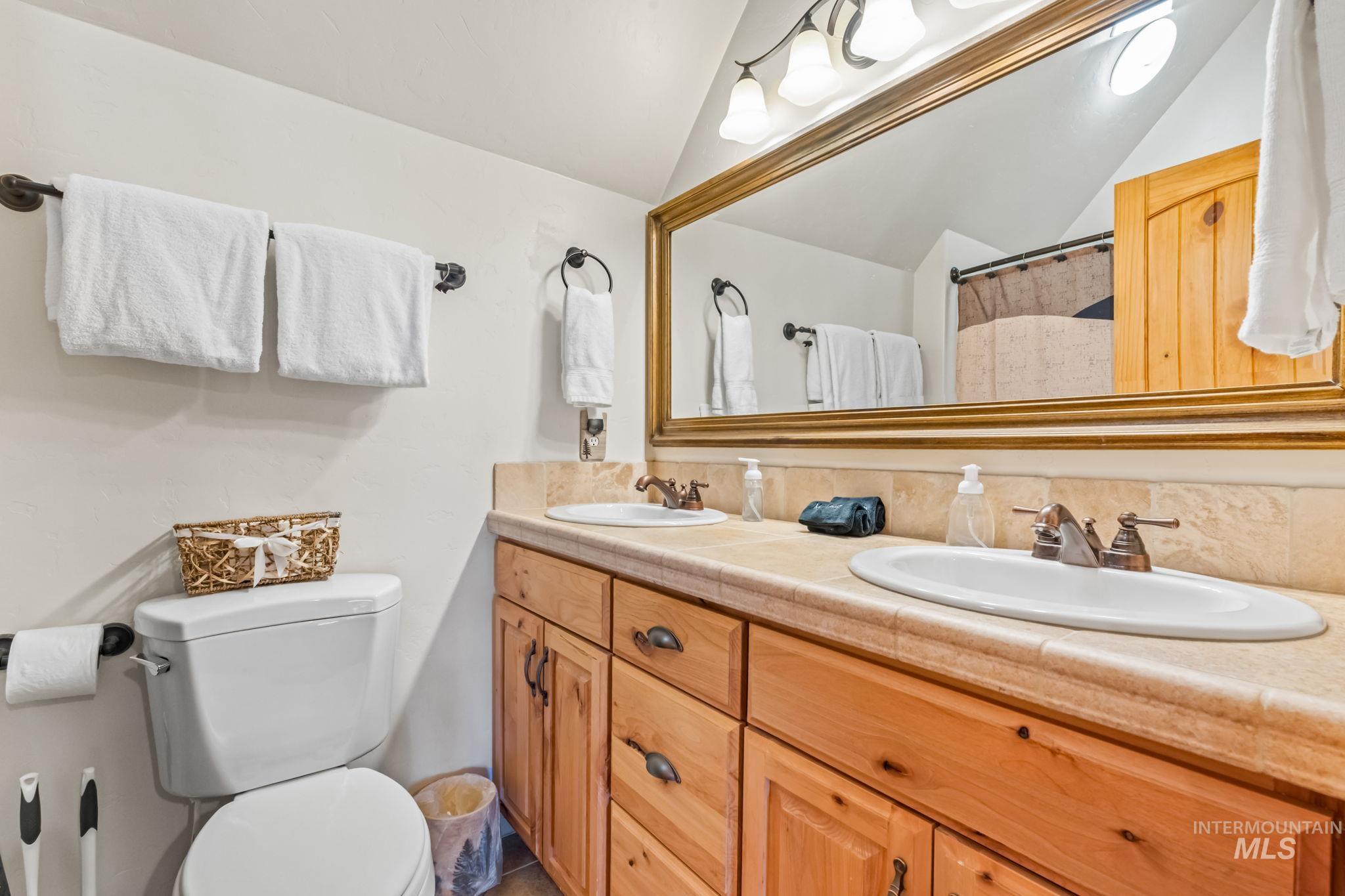 Full bath with a shower with shower curtain, double vanity, and vaulted ceiling