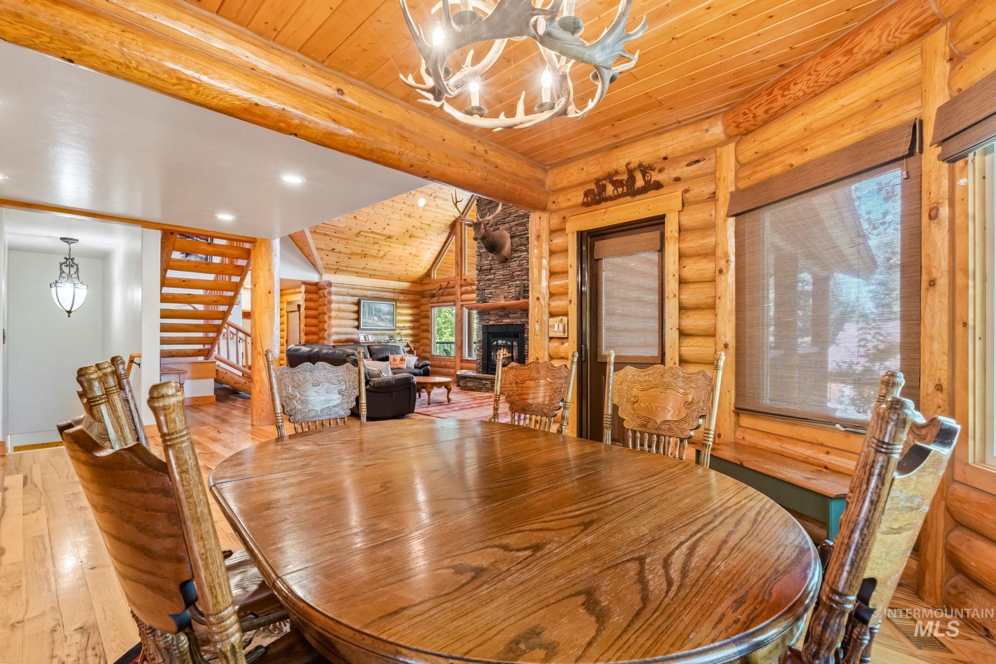 Dining room with stairway, wood-type flooring, log walls, wood ceiling, and a fireplace