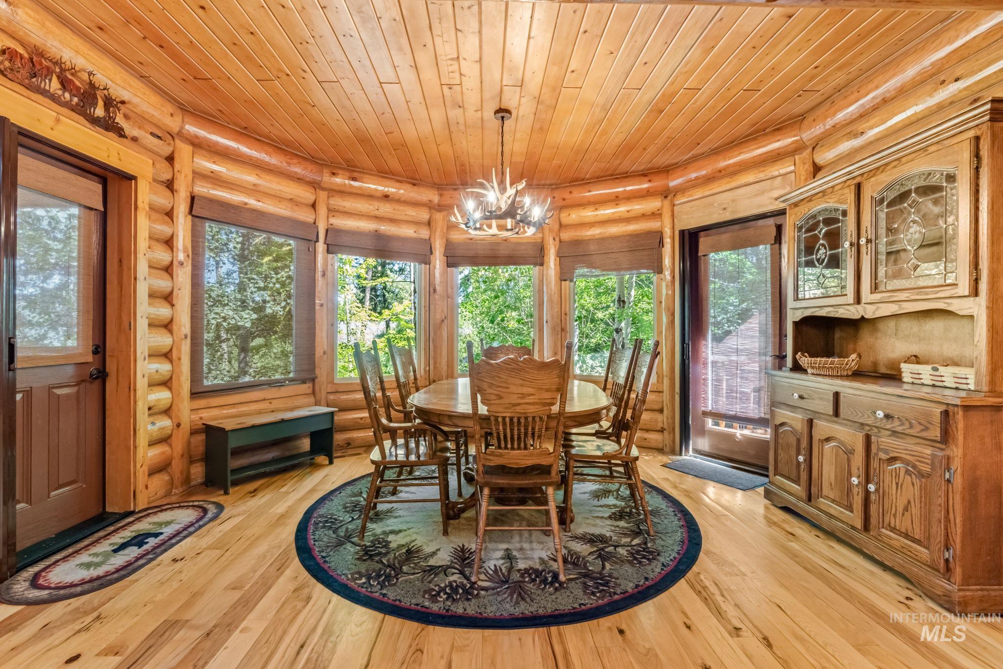 Dining area with log walls, wooden ceiling, light wood finished floors, and a chandelier