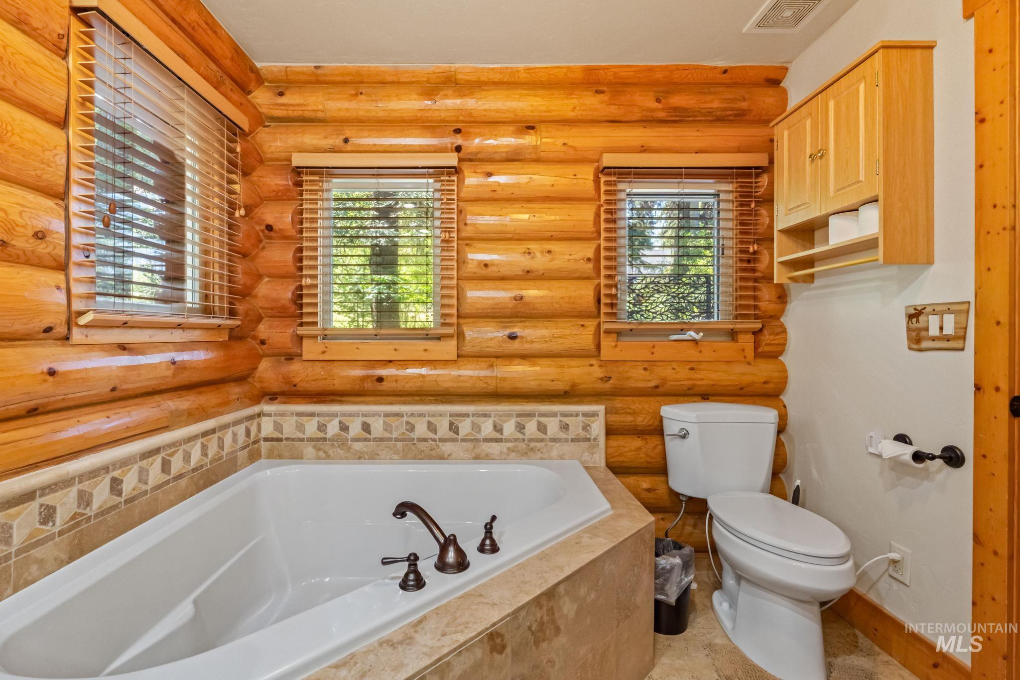 Full bathroom with a garden tub and log walls