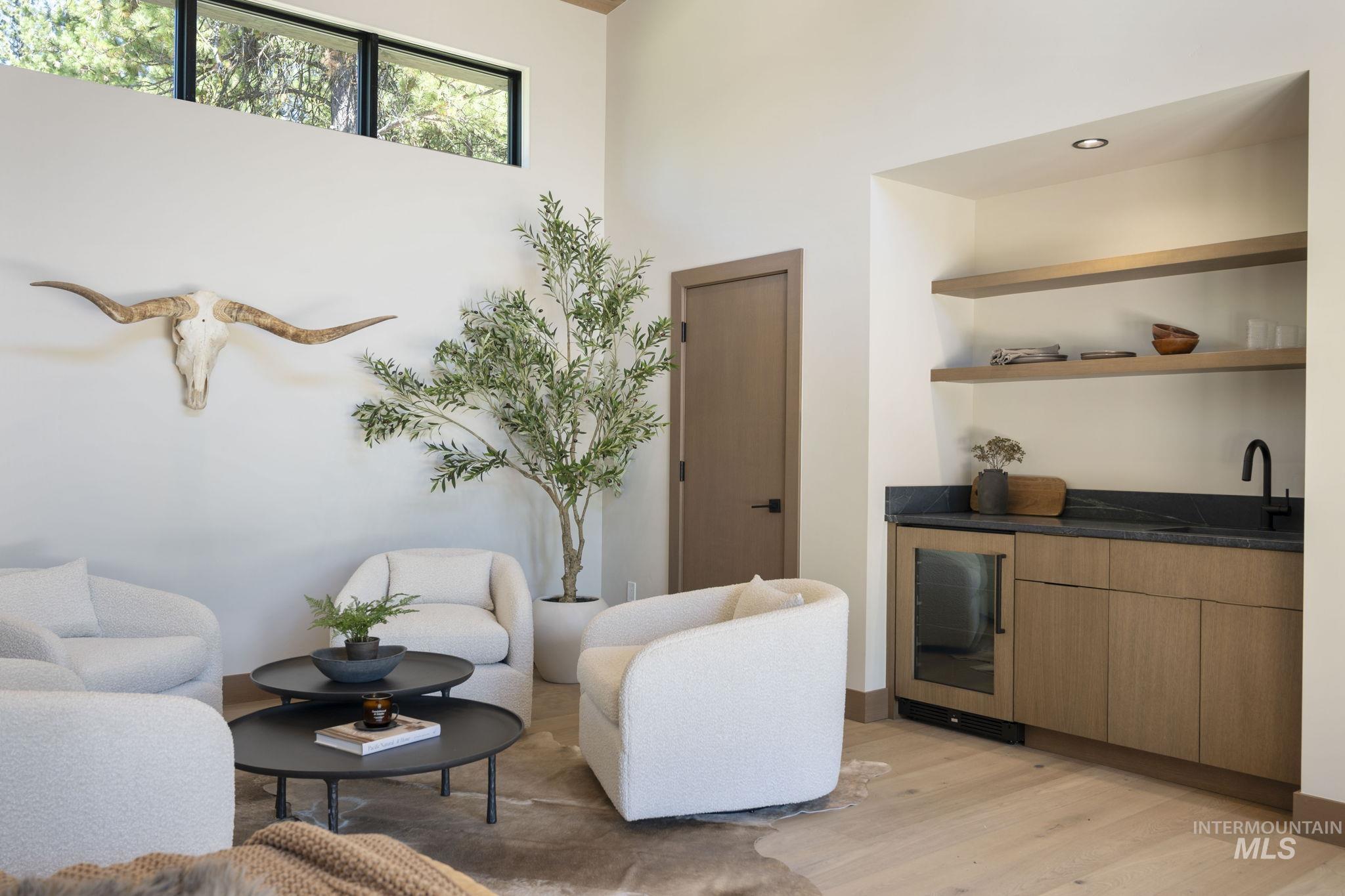 Bar area with light wood-style floors, beverage cooler, open shelves, and modern cabinets