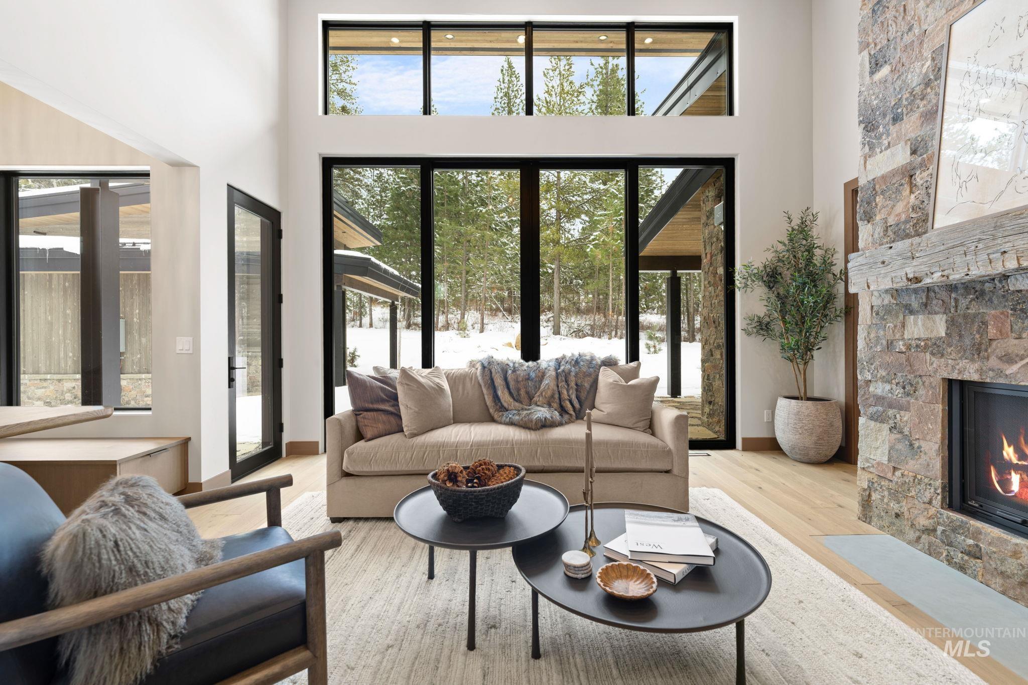 Living area featuring a stone fireplace, wood finished floors, a high ceiling, and healthy amount of natural light